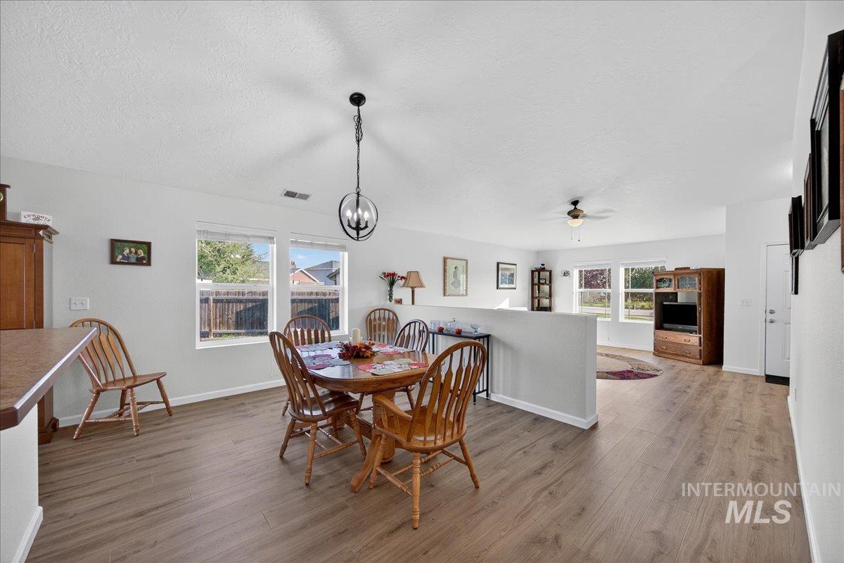 Dining area with light wood finished floors, a textured ceiling, a chandelier, and ceiling fan