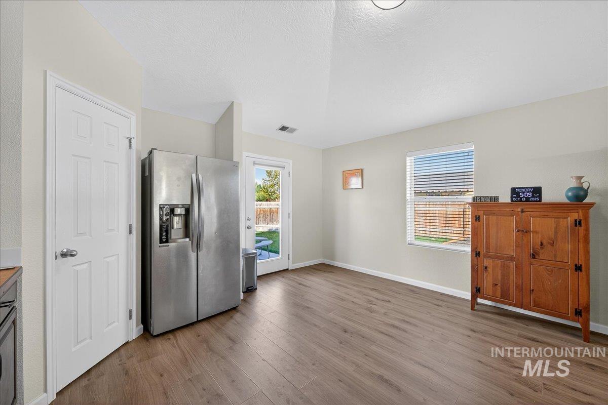 Kitchen with stainless steel fridge, dark wood-type flooring, and a textured ceiling