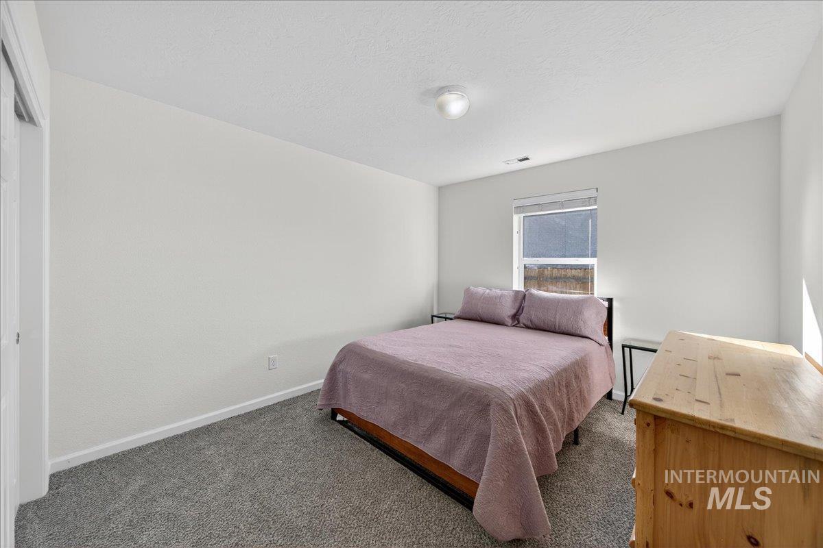 Carpeted bedroom featuring baseboards and a textured ceiling