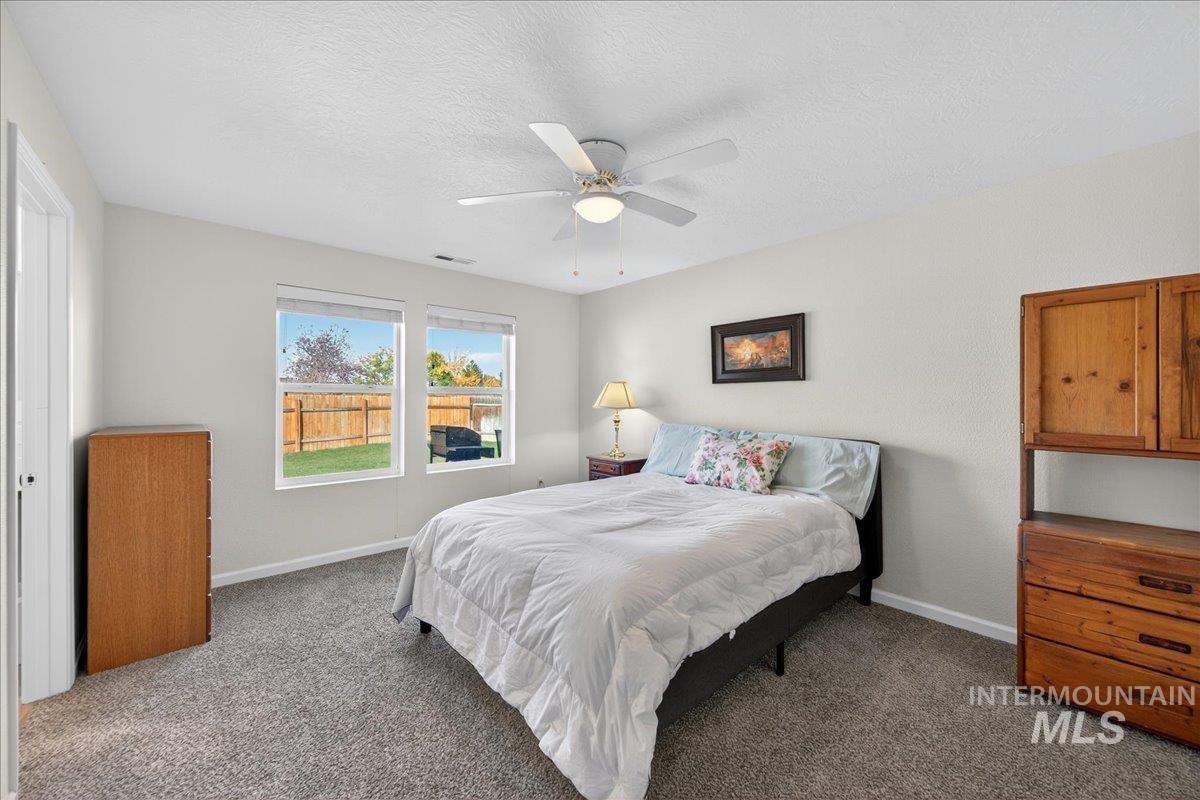 Bedroom featuring a textured ceiling, carpet floors, and ceiling fan