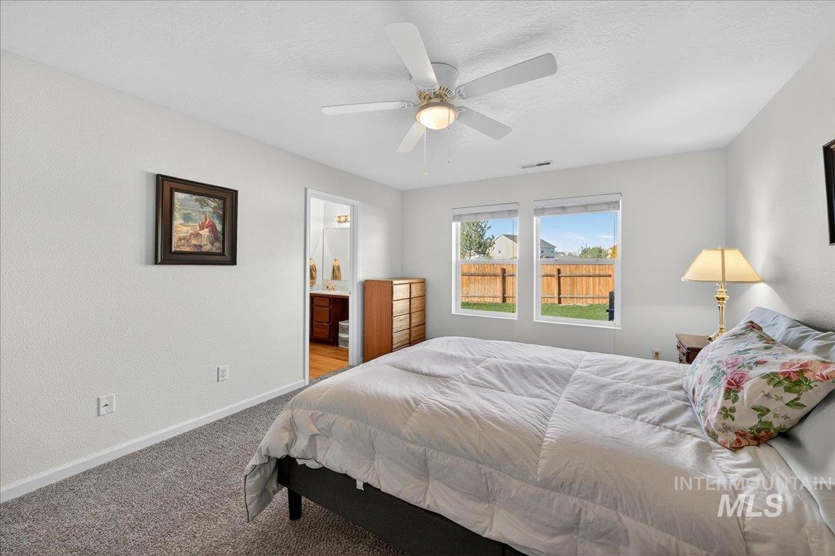 Bedroom with a textured ceiling, carpet, a ceiling fan, and a textured wall