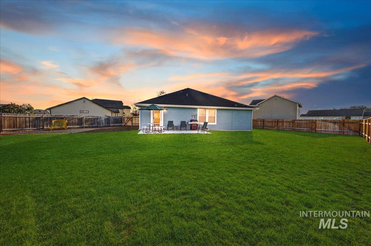 Back of property at dusk with a fenced backyard and a patio area