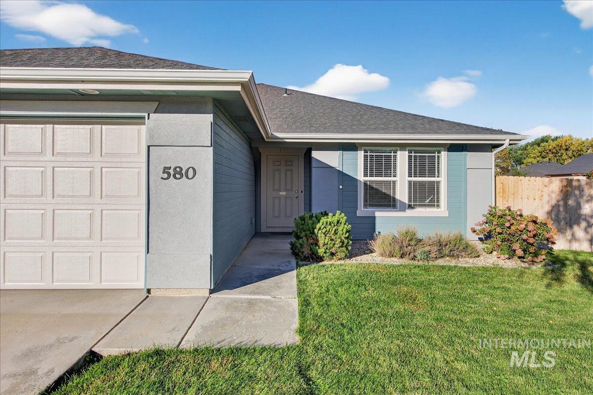 Property entrance with an attached garage and a shingled roof