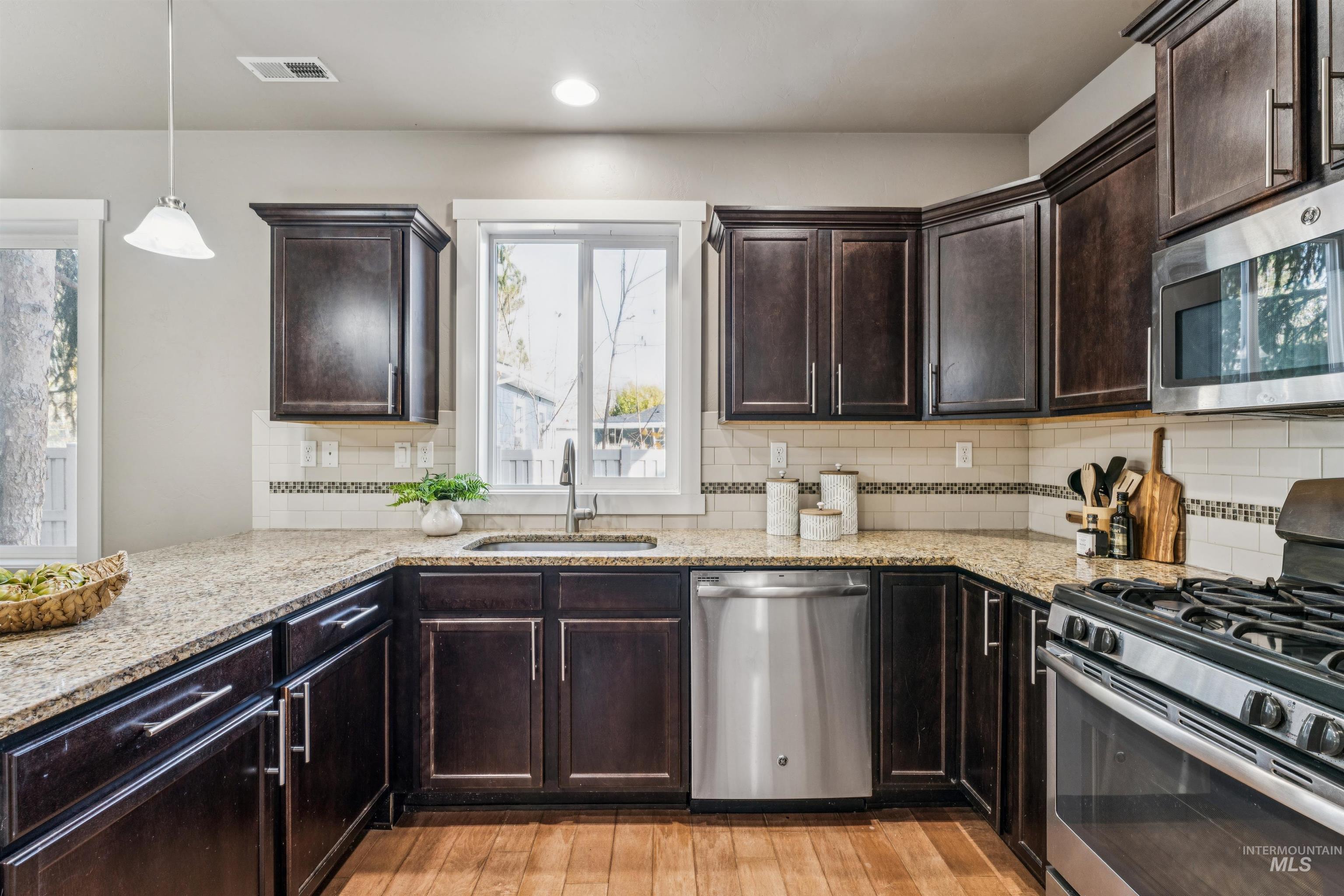 Kitchen with stainless steel appliances, dark brown cabinets, light wood finished floors, and recessed lighting