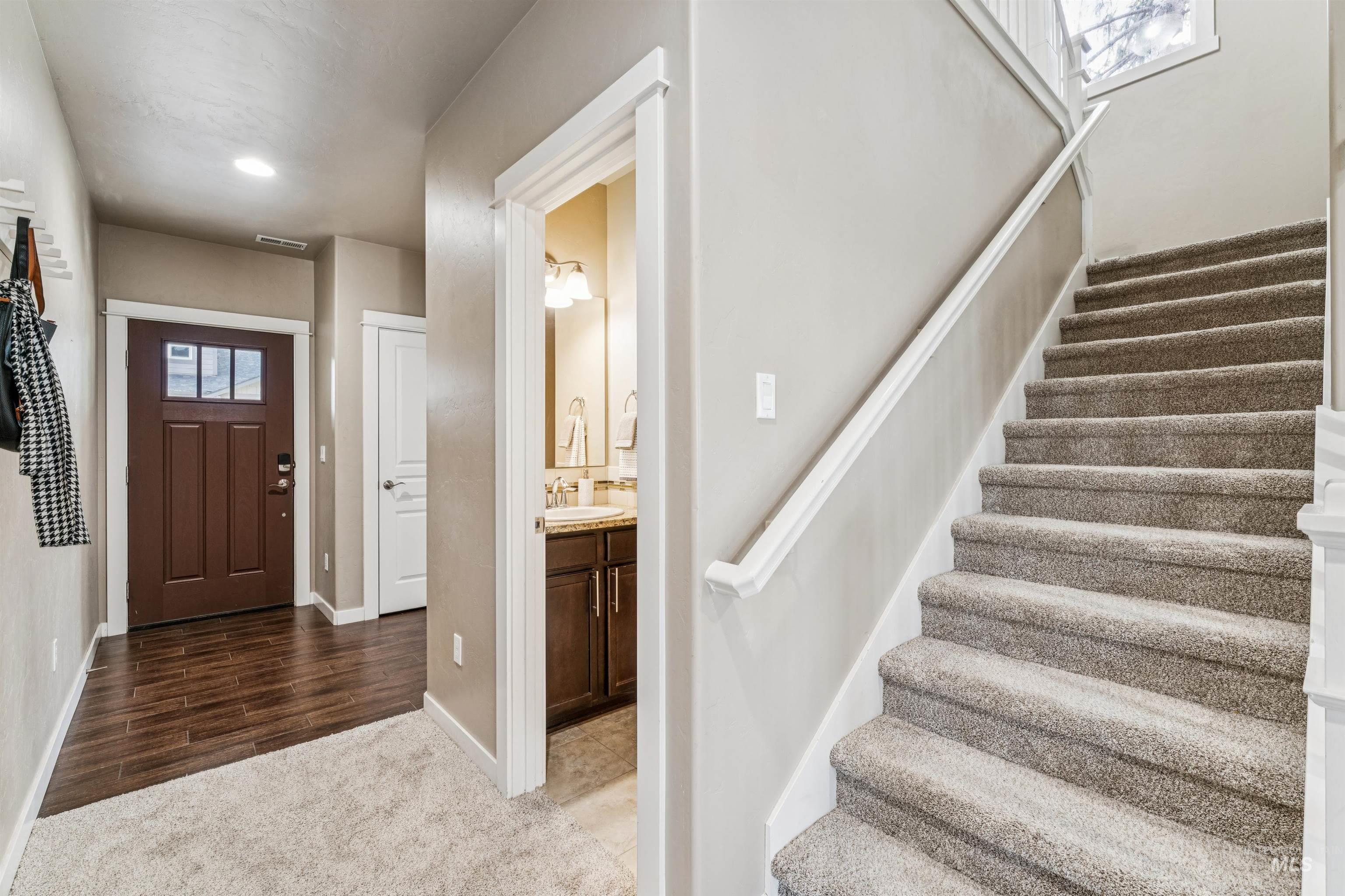 Carpeted foyer with stairs and baseboards