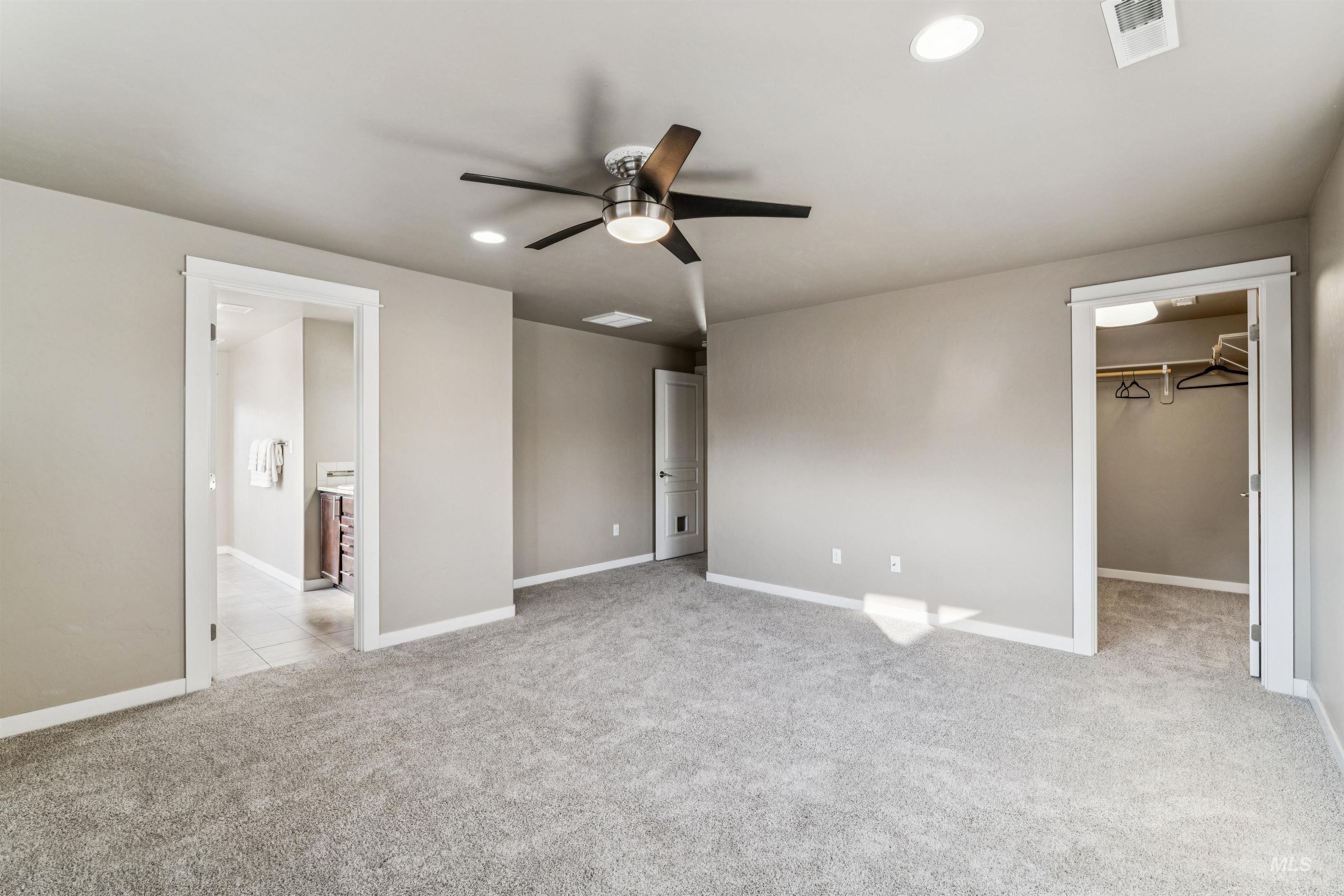 Unfurnished bedroom with light carpet, a spacious closet, recessed lighting, and ceiling fan