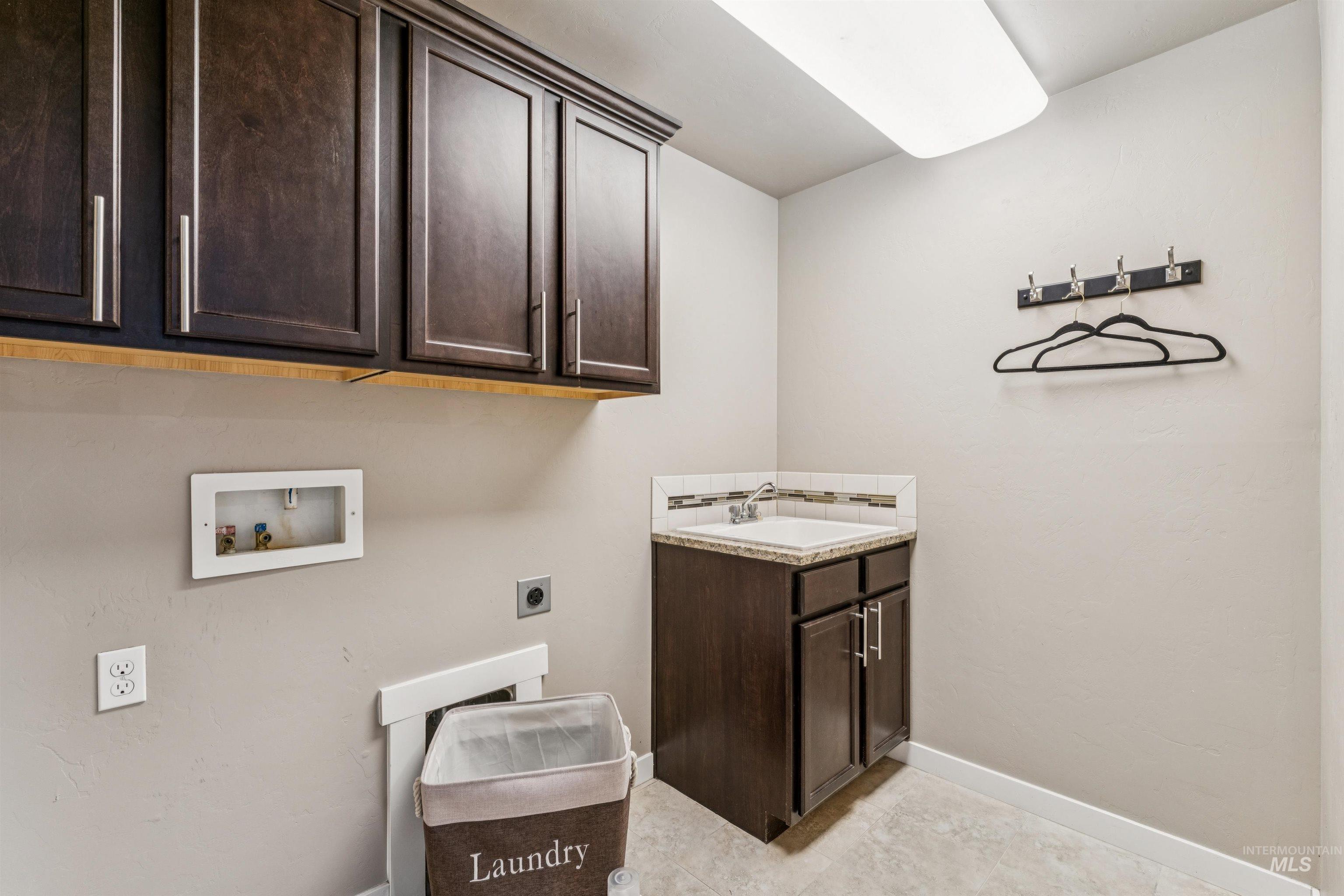 Washroom featuring cabinet space, hookup for a washing machine, electric dryer hookup, and light tile patterned flooring