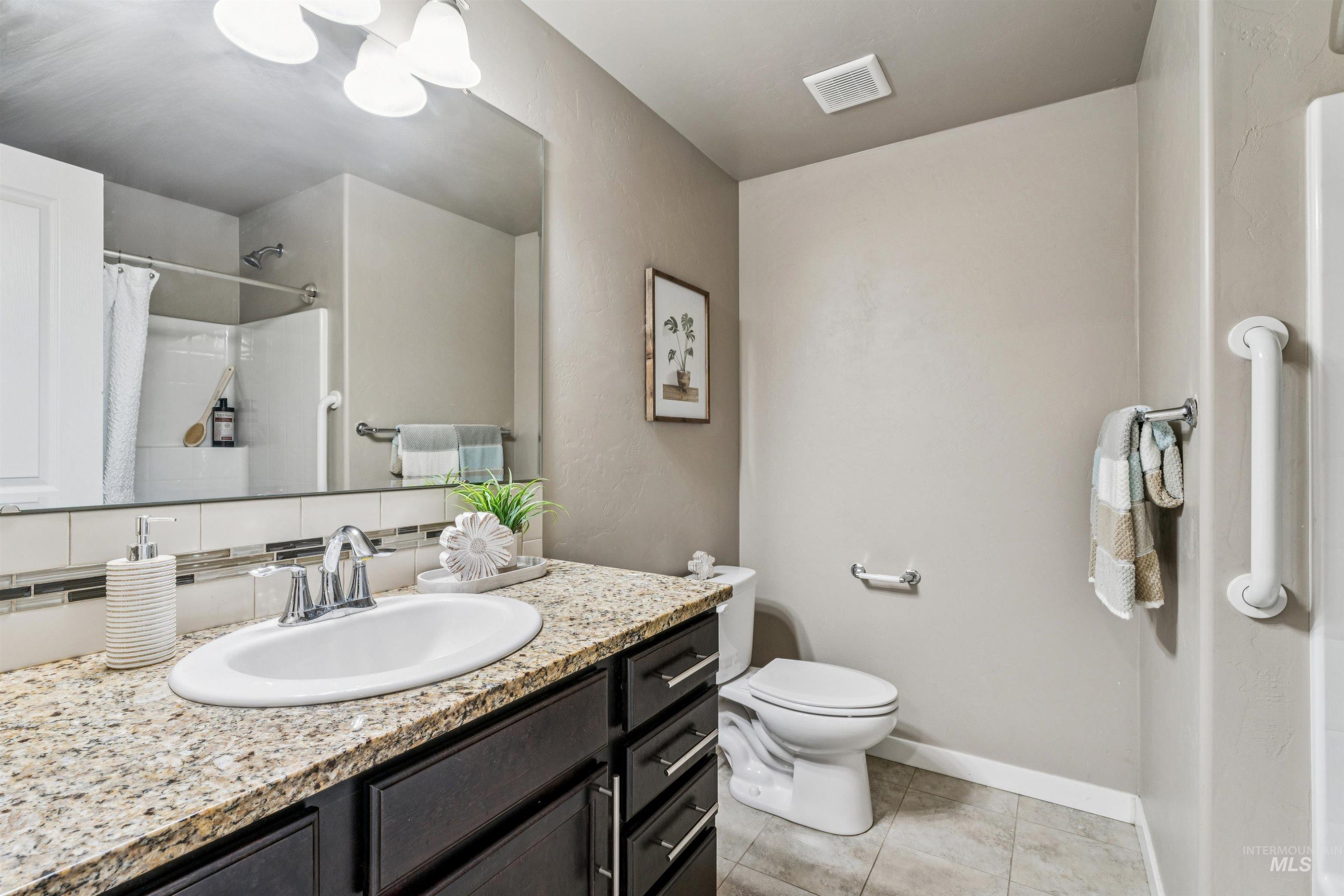 Full bathroom with curtained shower, vanity, and light tile patterned floors