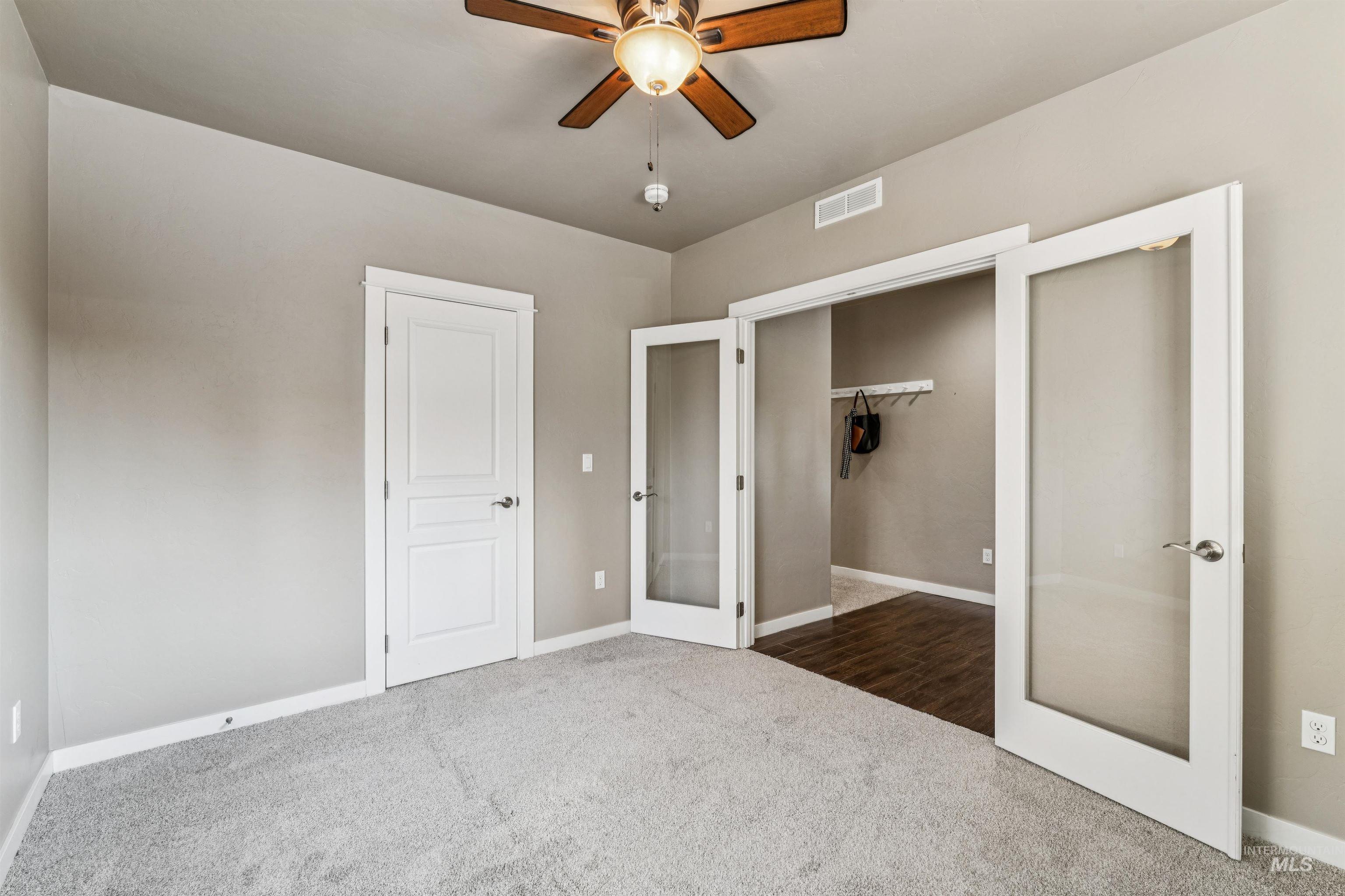 Unfurnished bedroom with french doors, dark carpet, ceiling fan, and a closet