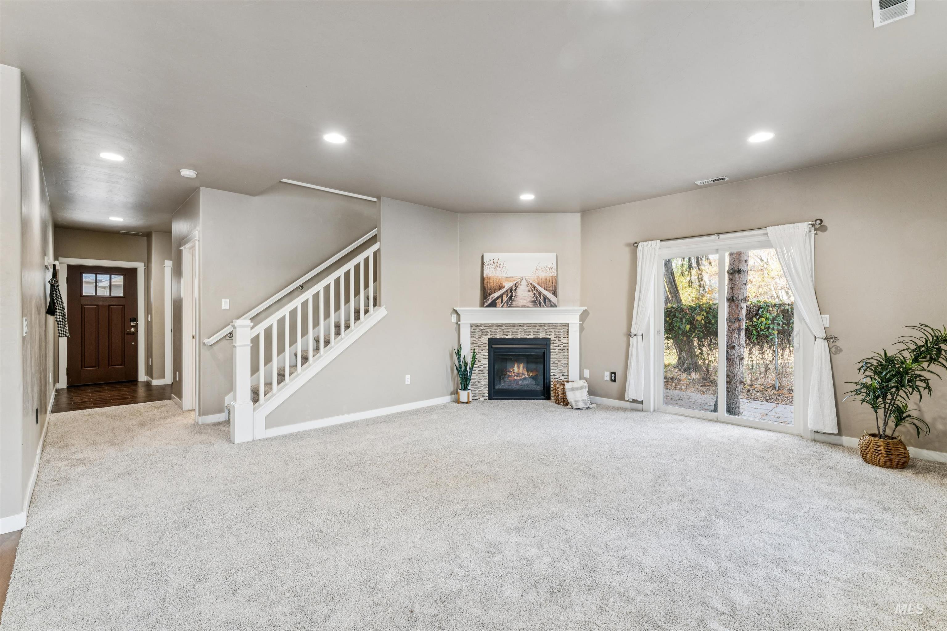 Unfurnished living room with recessed lighting, carpet, a tile fireplace, and stairway