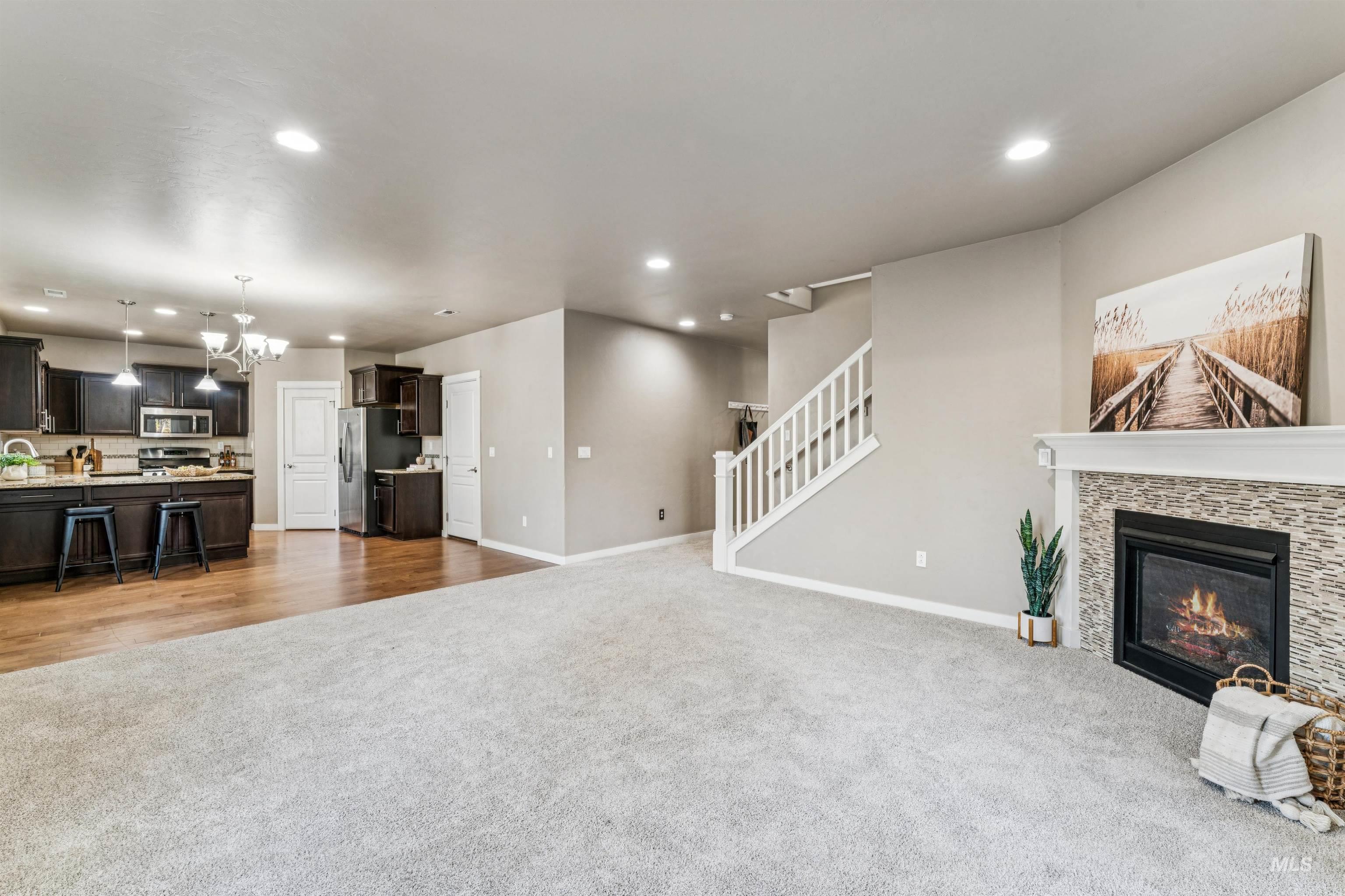 Living room featuring dark colored carpet, a chandelier, recessed lighting, stairs, and a fireplace