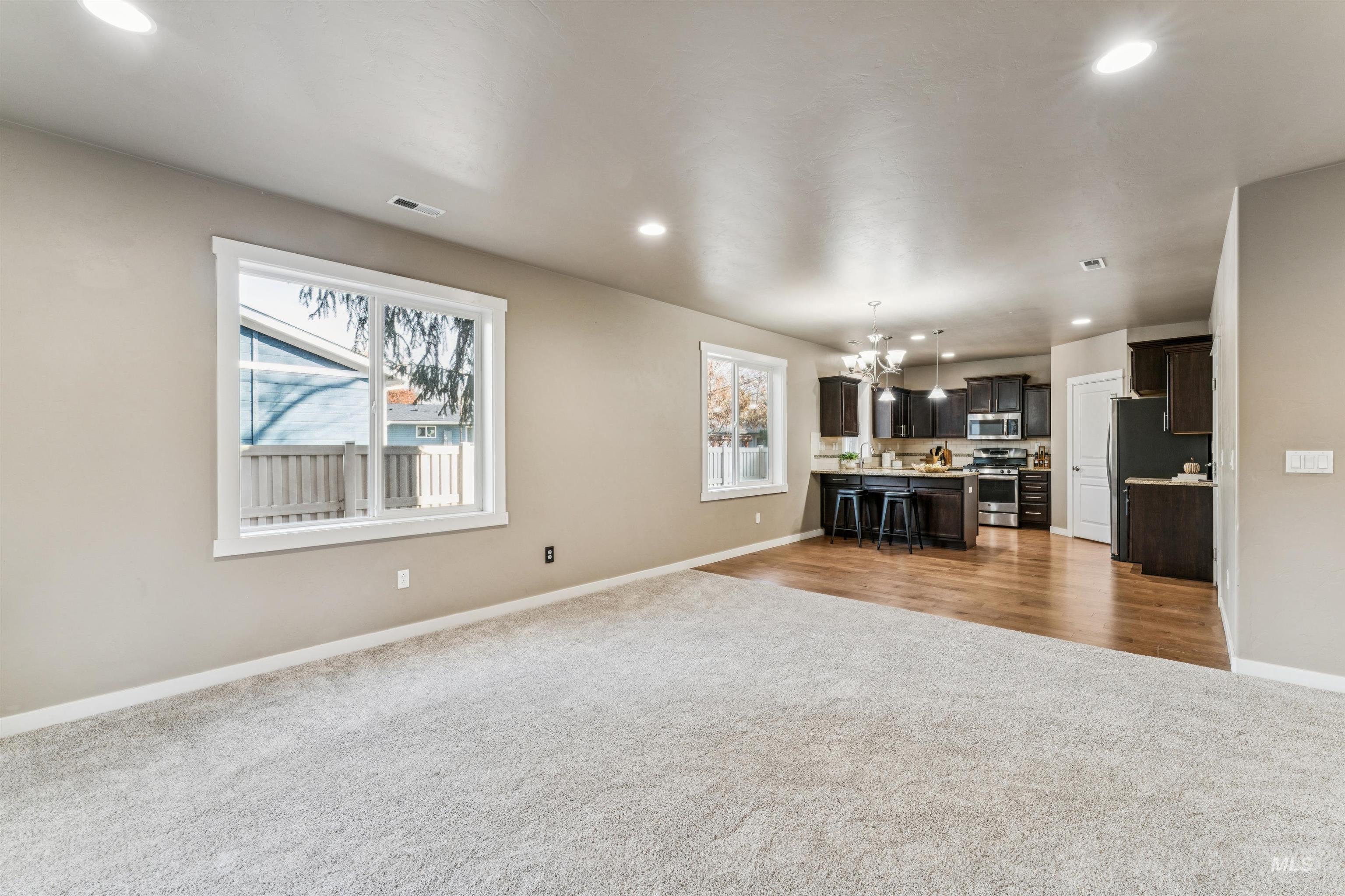 Unfurnished living room with dark carpet, a chandelier, recessed lighting, and healthy amount of natural light