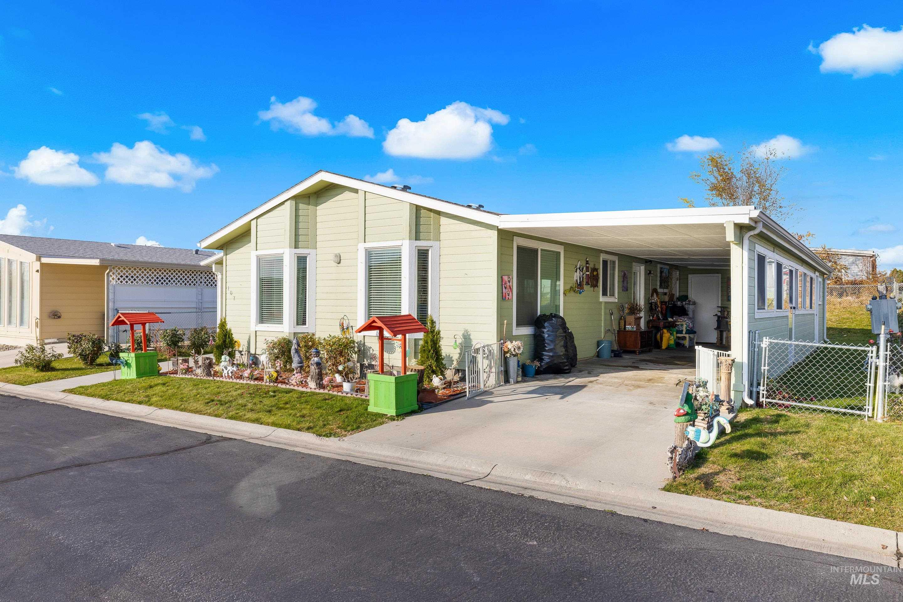 Manufactured / mobile home with a front lawn, a carport, a gate, and driveway