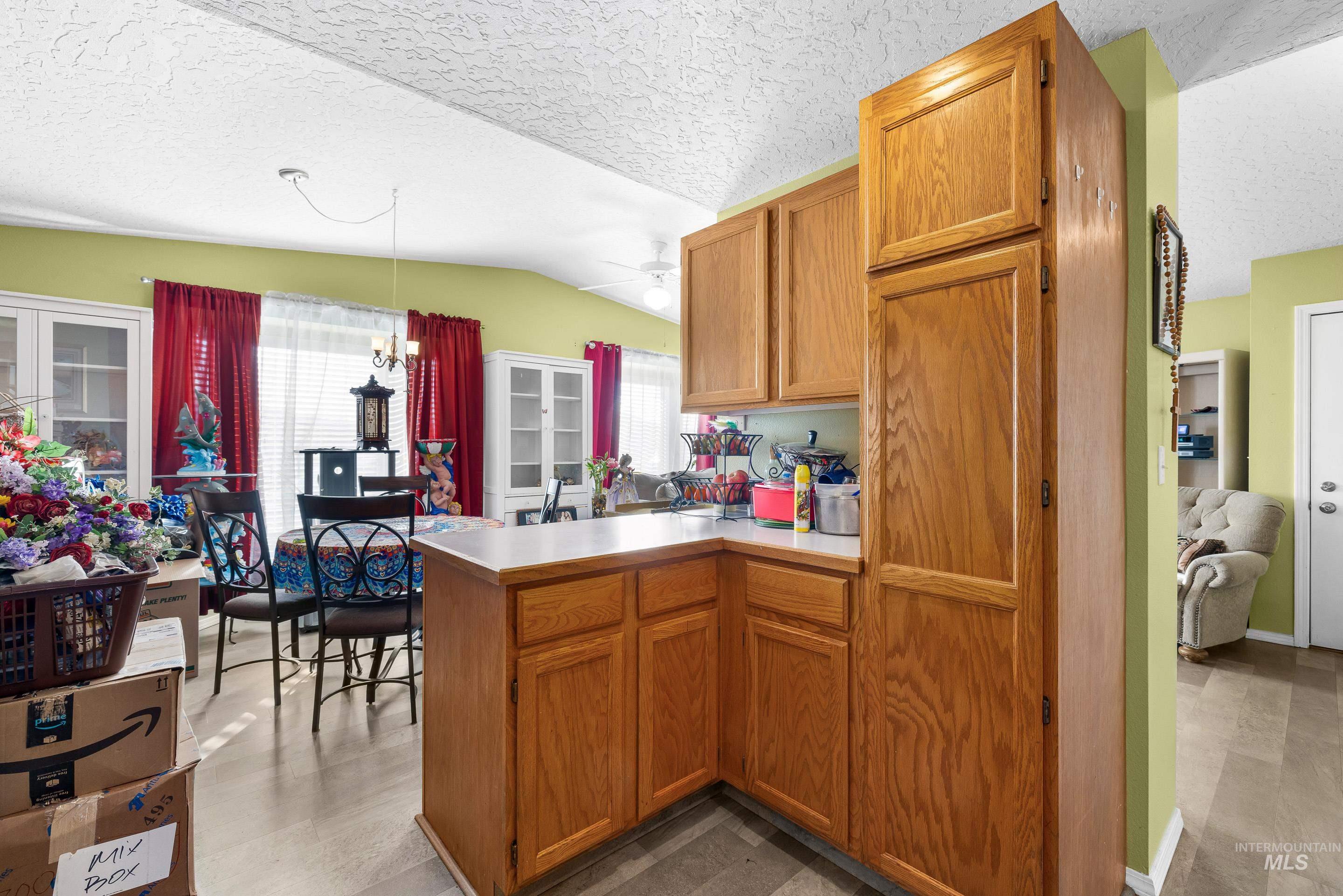Kitchen featuring vaulted ceiling, a peninsula, a textured ceiling, ceiling fan, and light countertops