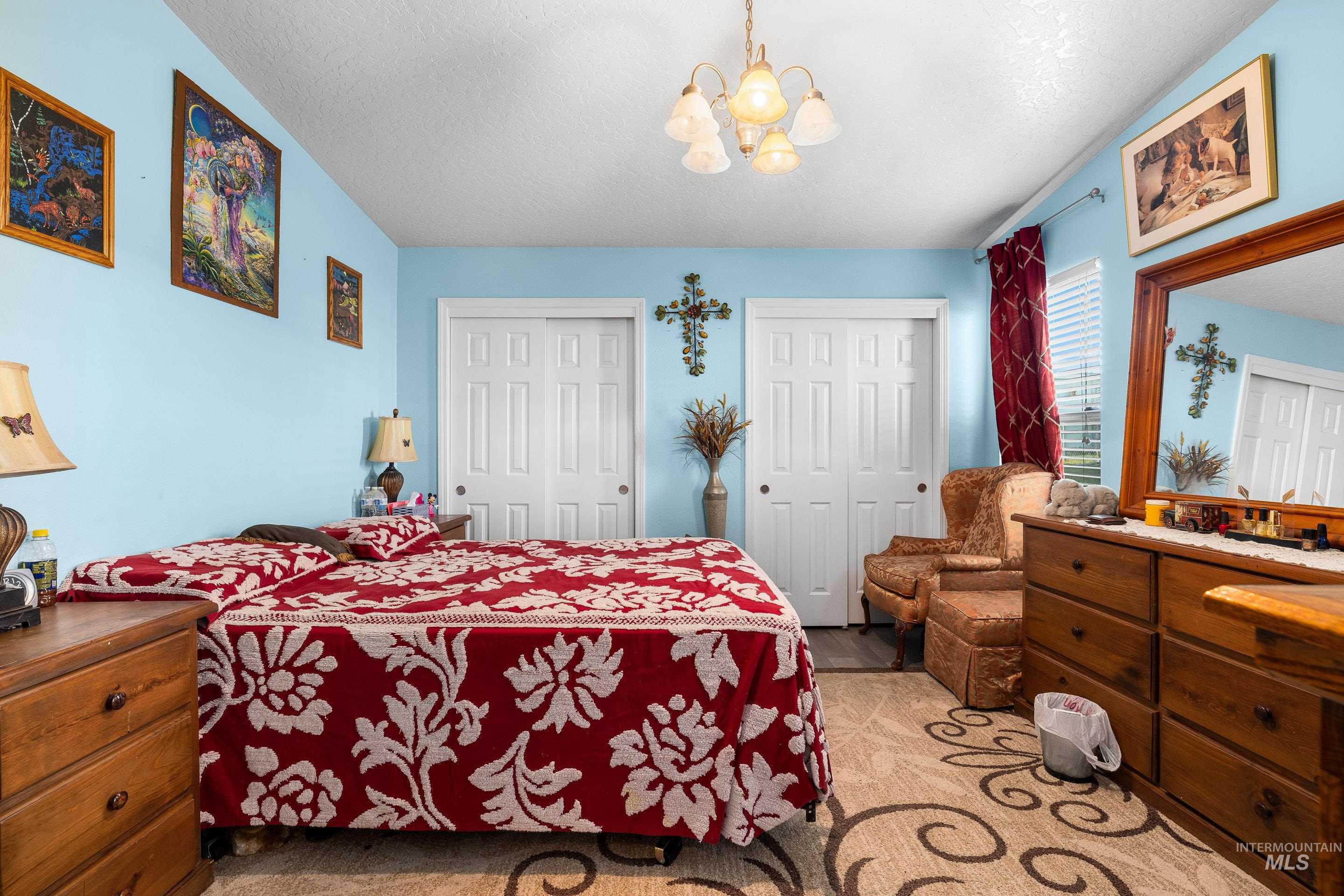 Bedroom with multiple closets, a chandelier, and a textured ceiling