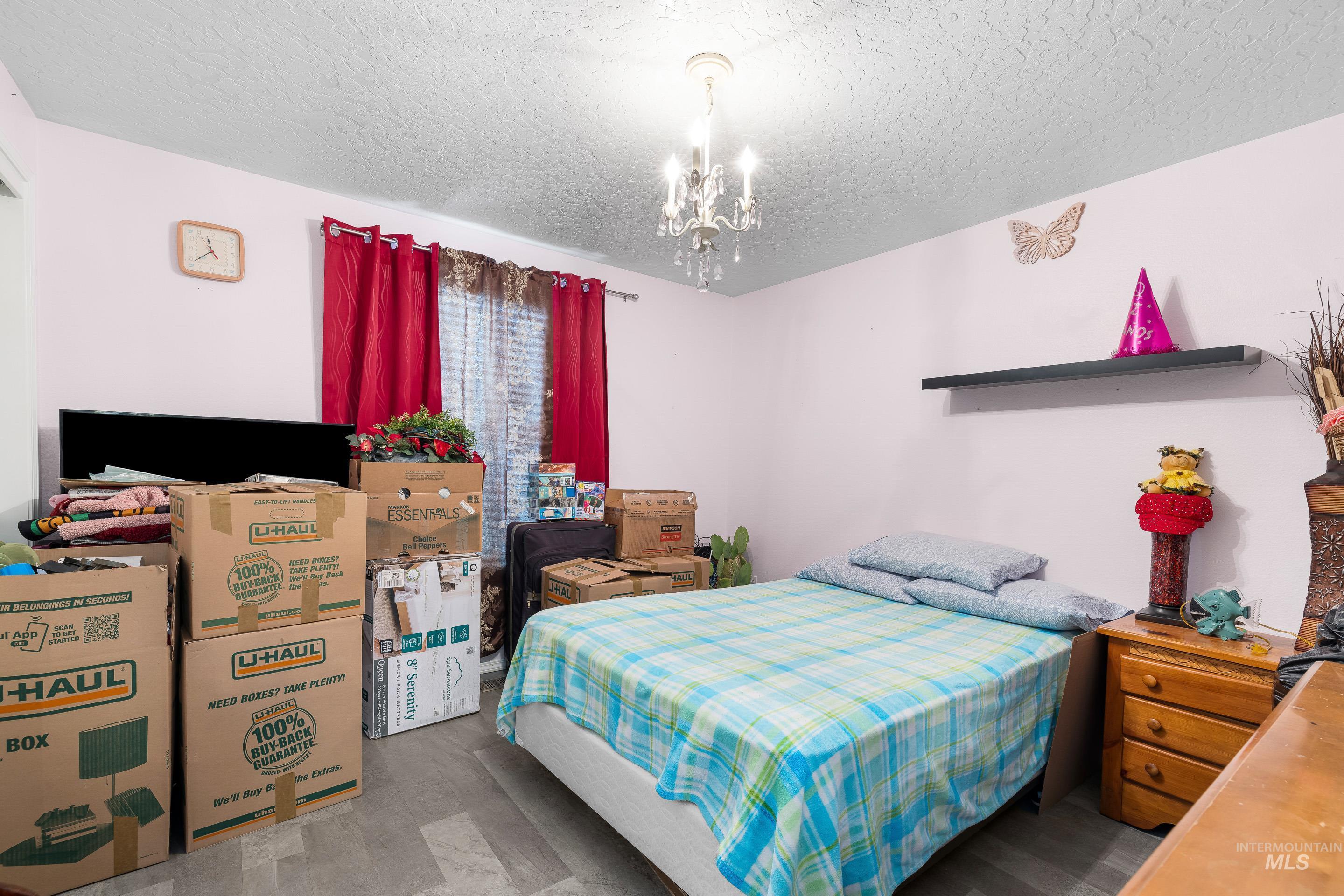 Bedroom with a textured ceiling, a chandelier, and wood finished floors
