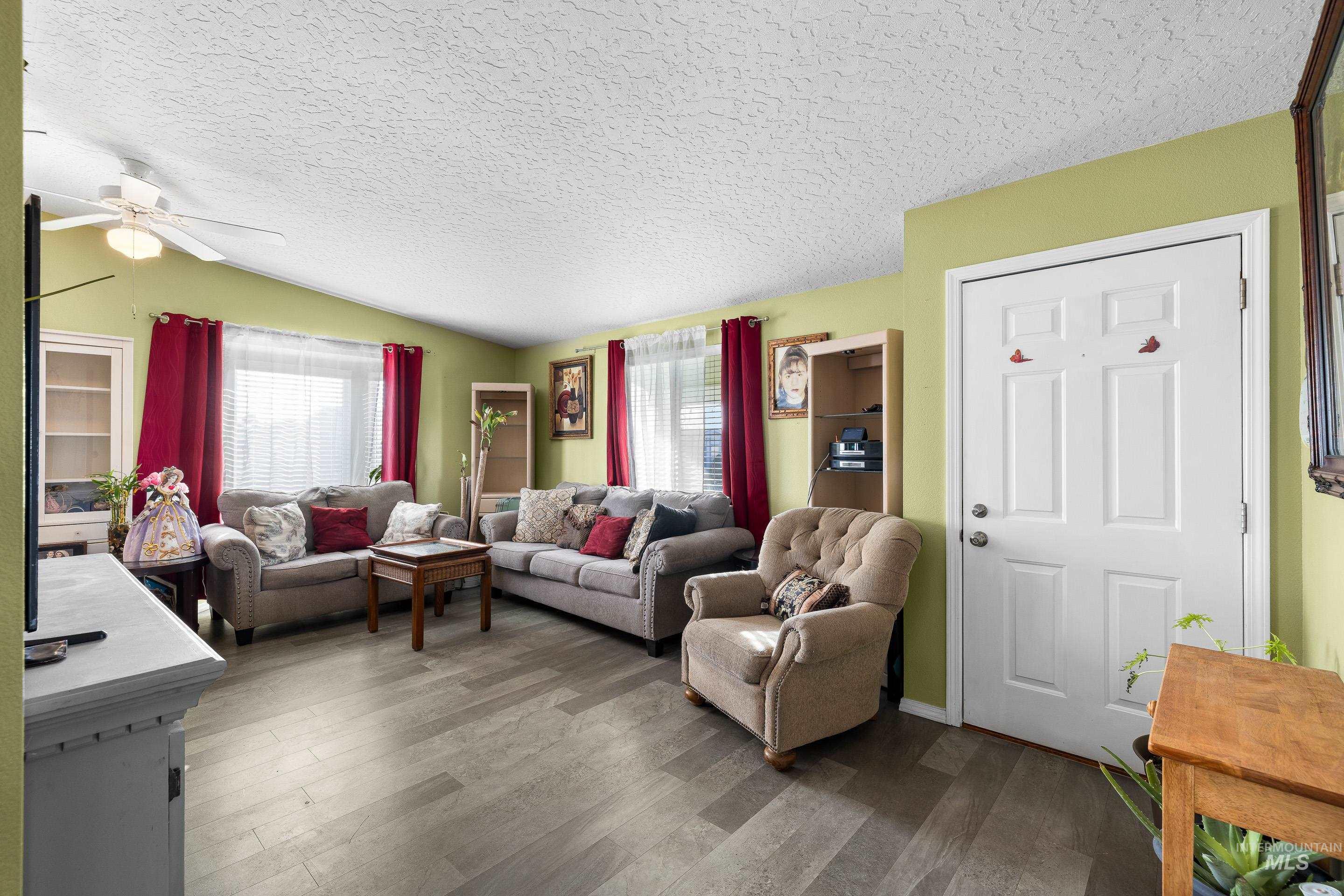 Living area featuring a textured ceiling, wood finished floors, lofted ceiling, and ceiling fan