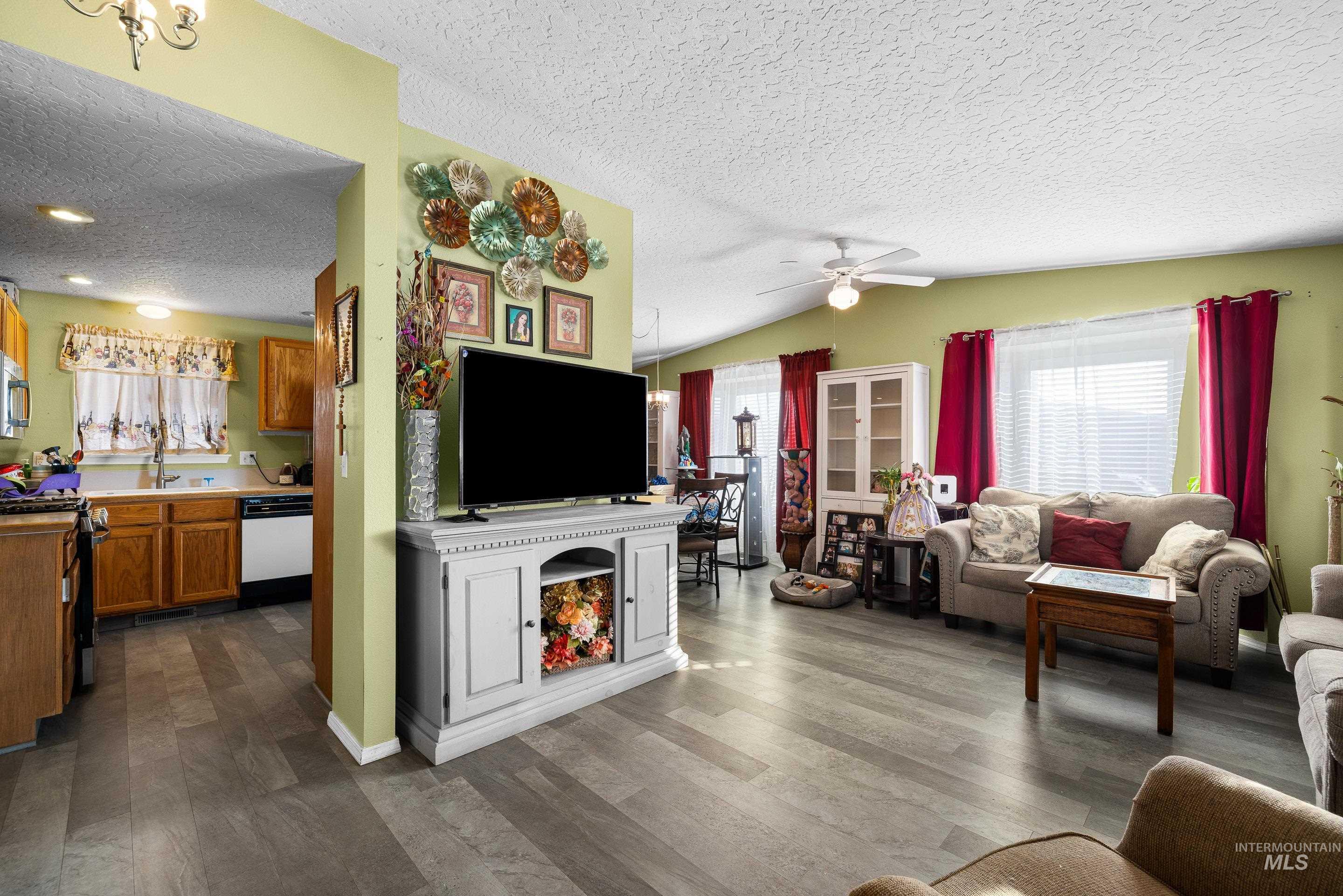 Living area featuring a textured ceiling, dark wood finished floors, ceiling fan, and vaulted ceiling