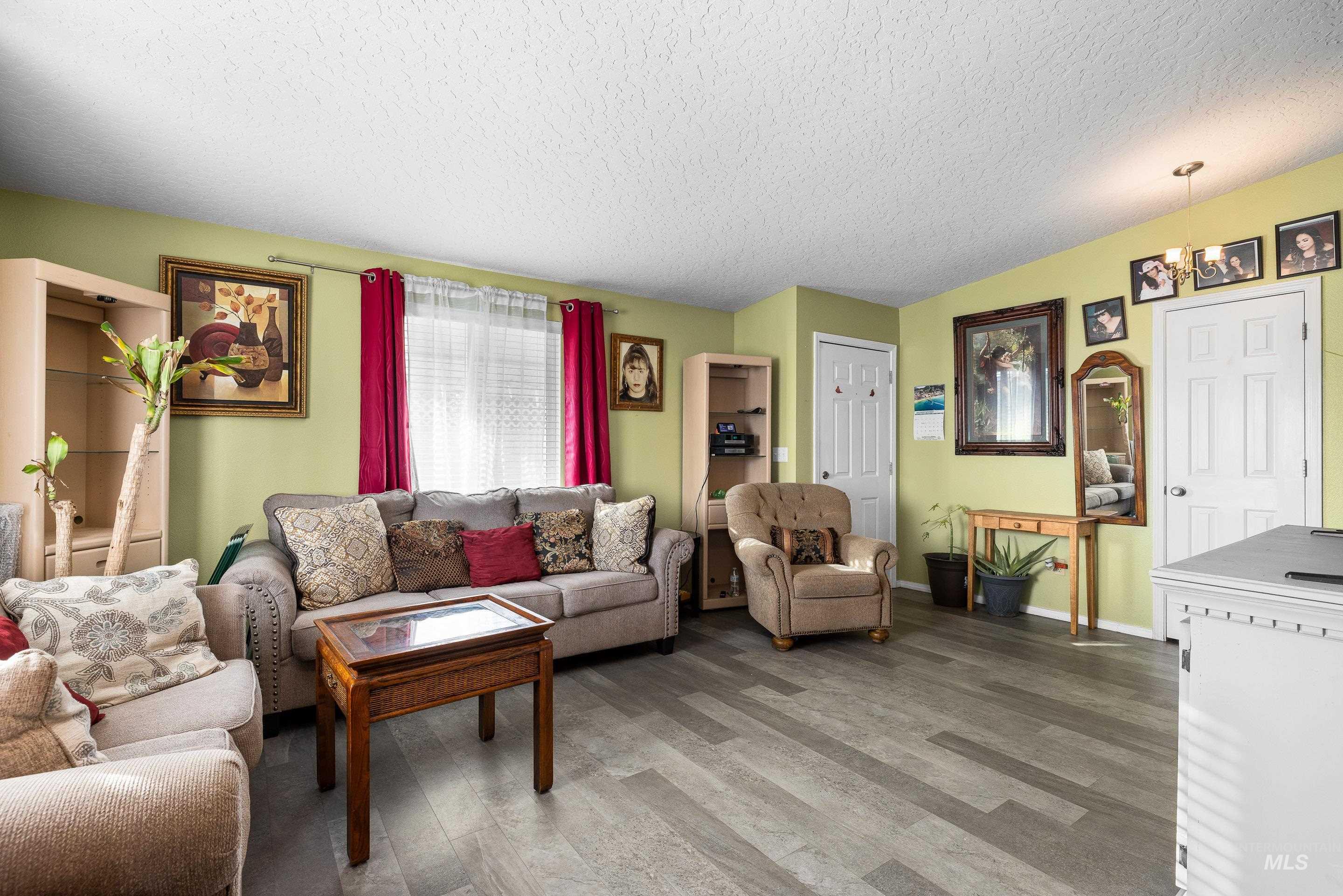 Living area featuring a textured ceiling, wood finished floors, and a chandelier