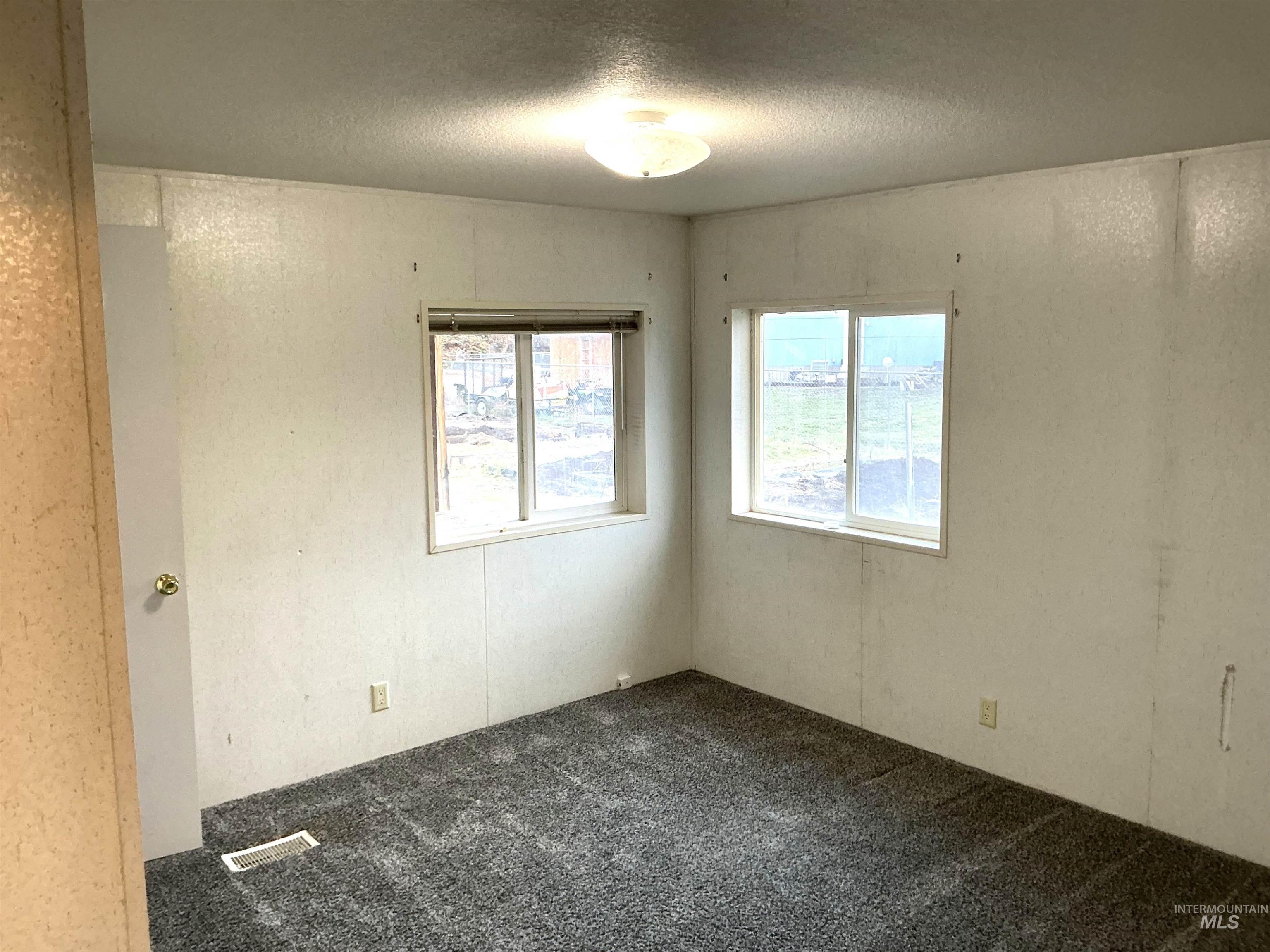 Empty room with carpet floors and a textured ceiling