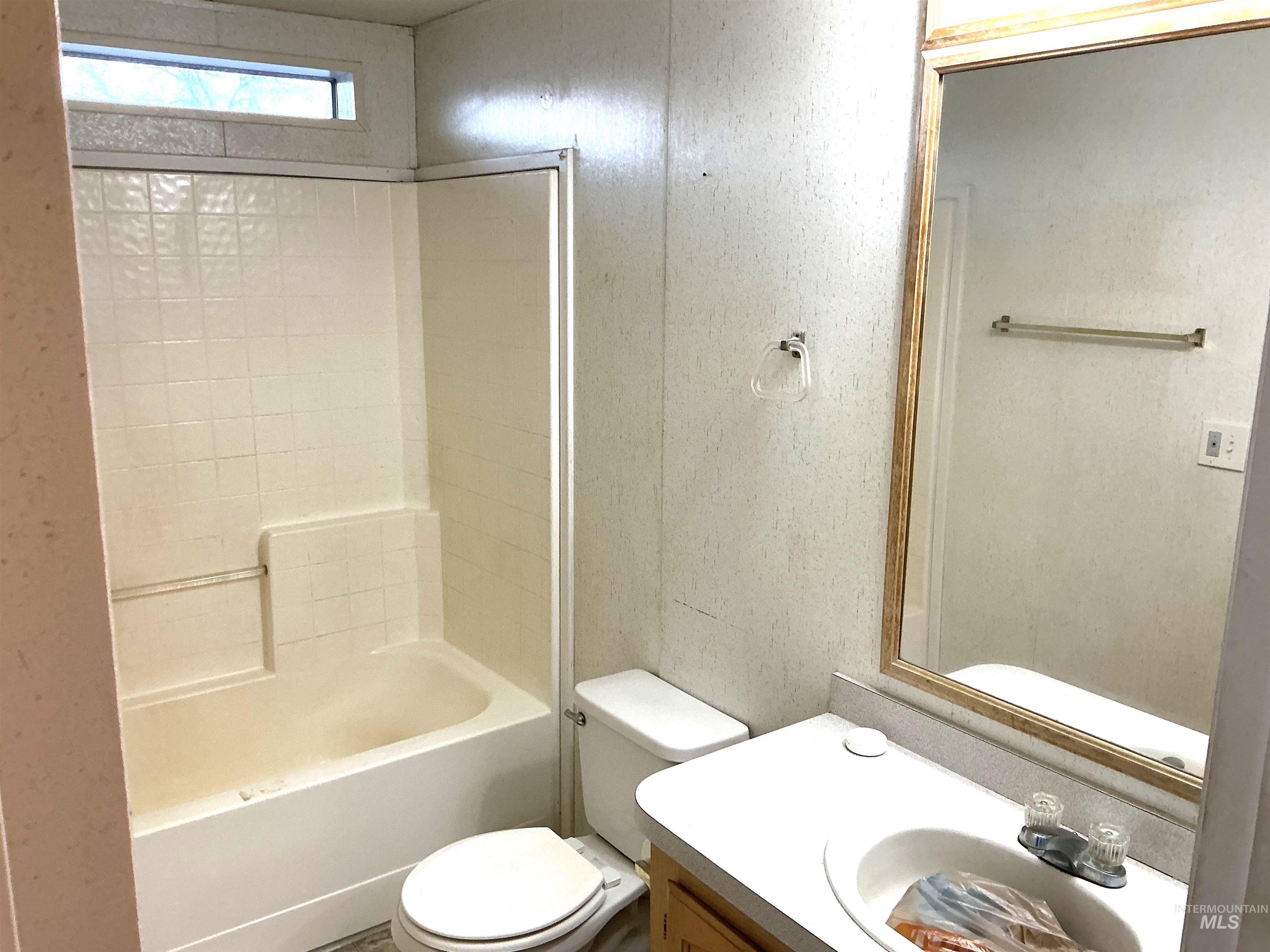 Bathroom with vanity, shower / bathtub combination, and a textured wall