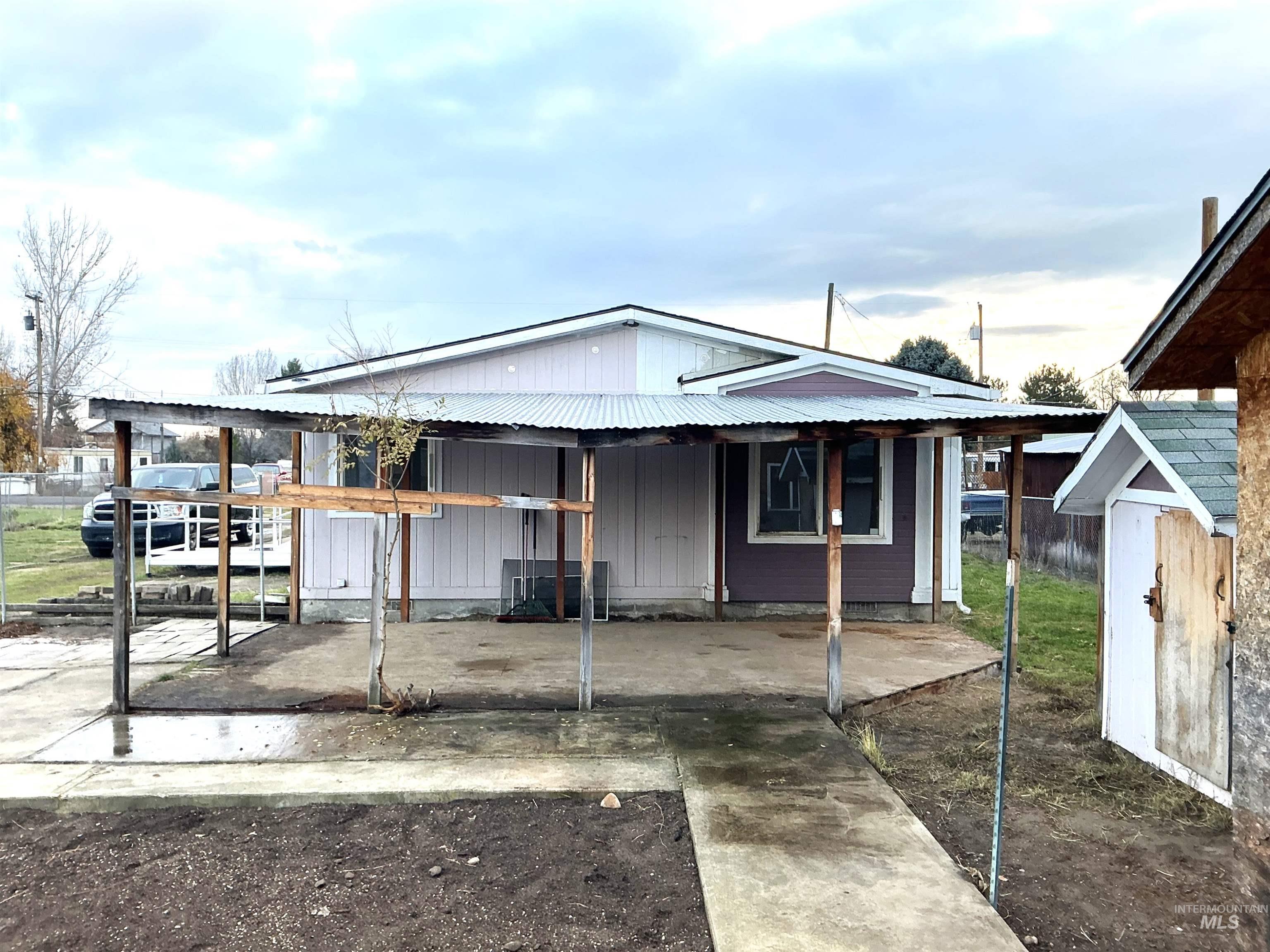 View of front of home featuring a porch, a metal roof, and a shed