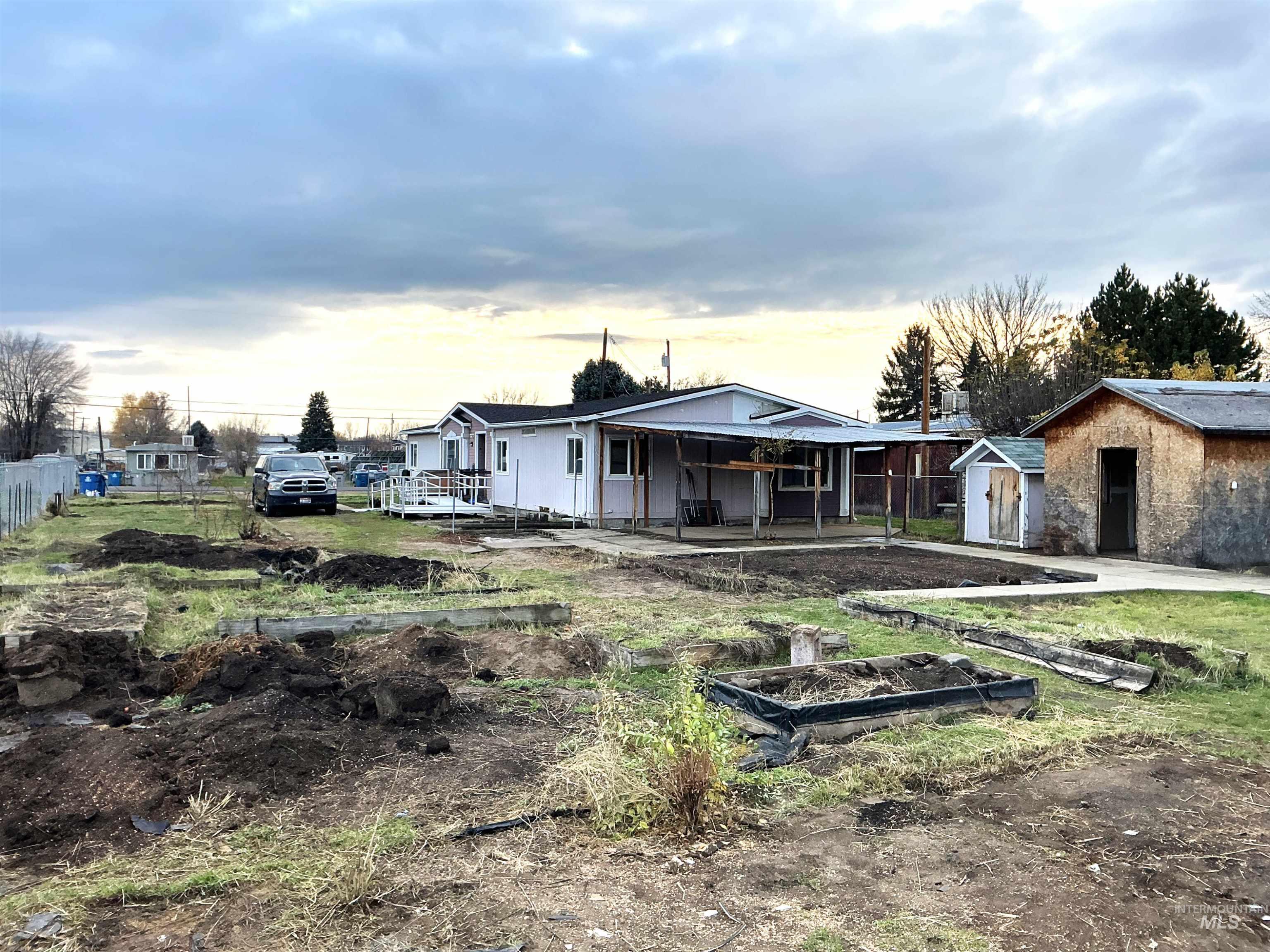 Rear view of property featuring a vegetable garden, a storage shed, and a patio area