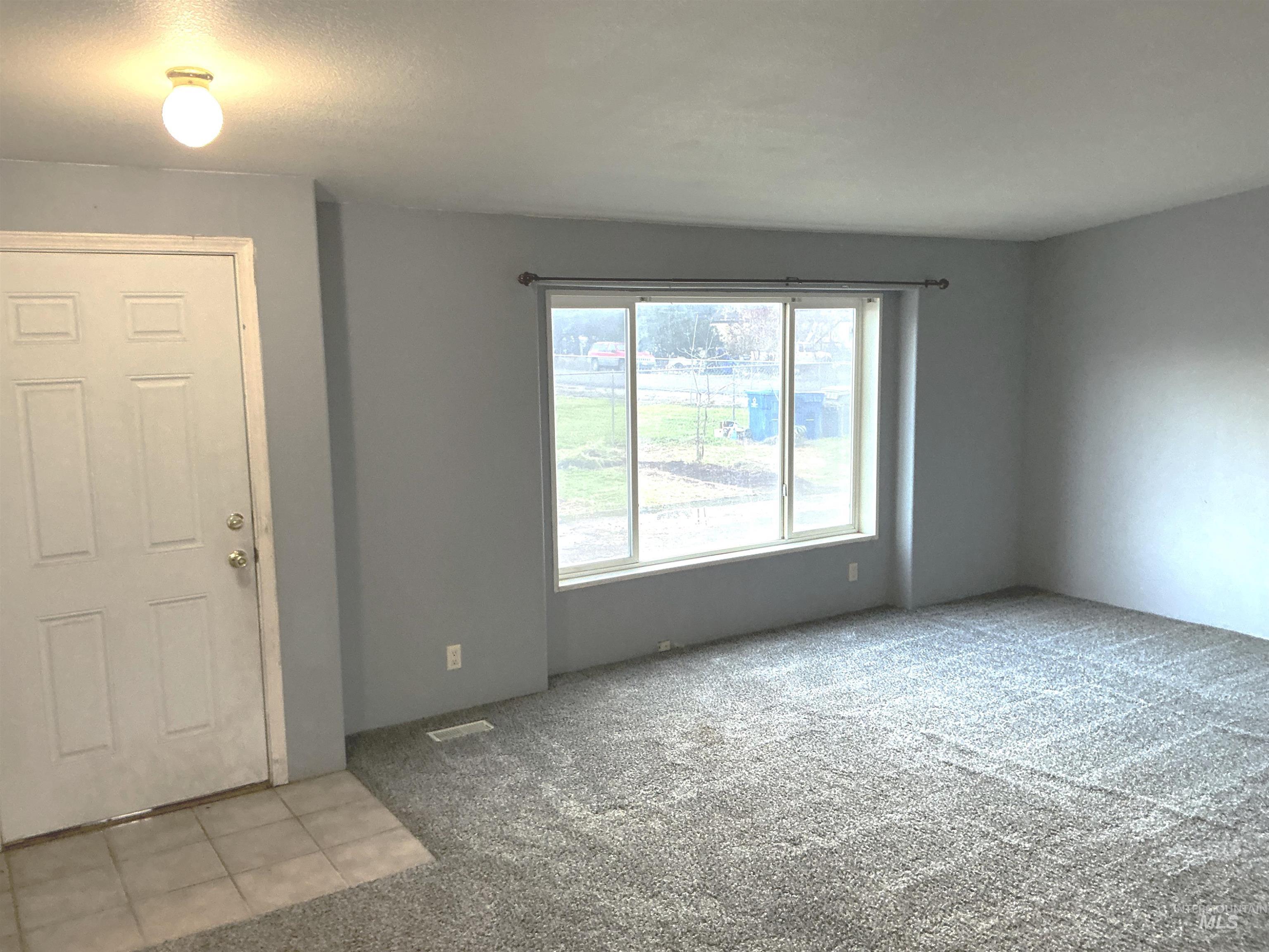 Foyer entrance with light colored carpet and light tile patterned flooring