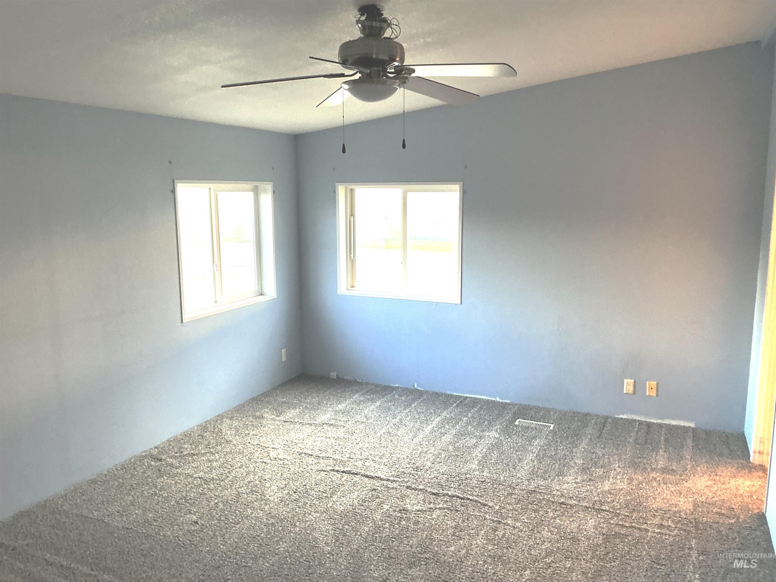 Empty room featuring carpet floors and a ceiling fan