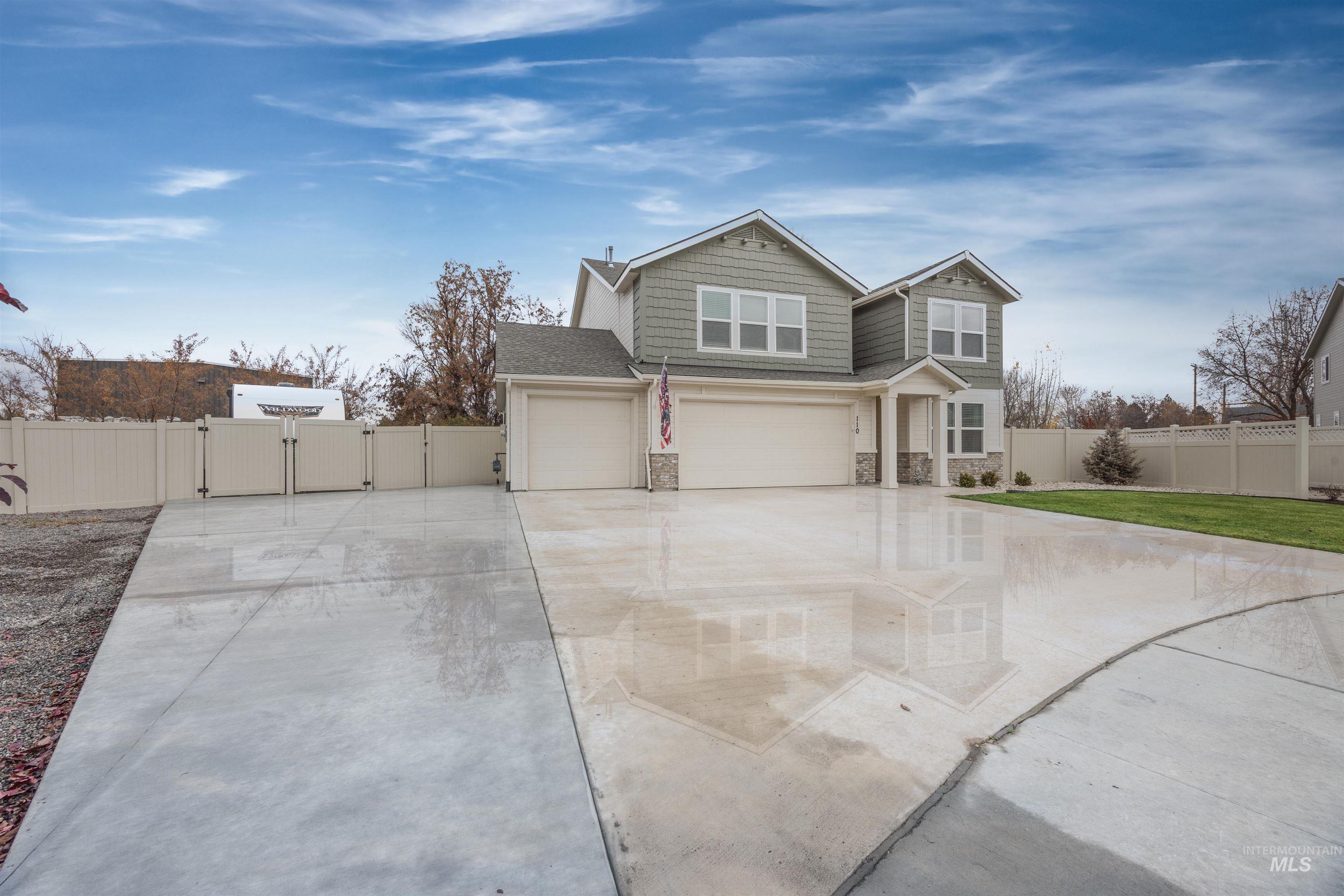 View of front of home featuring stone siding, concrete driveway, a gate, and an attached garage
