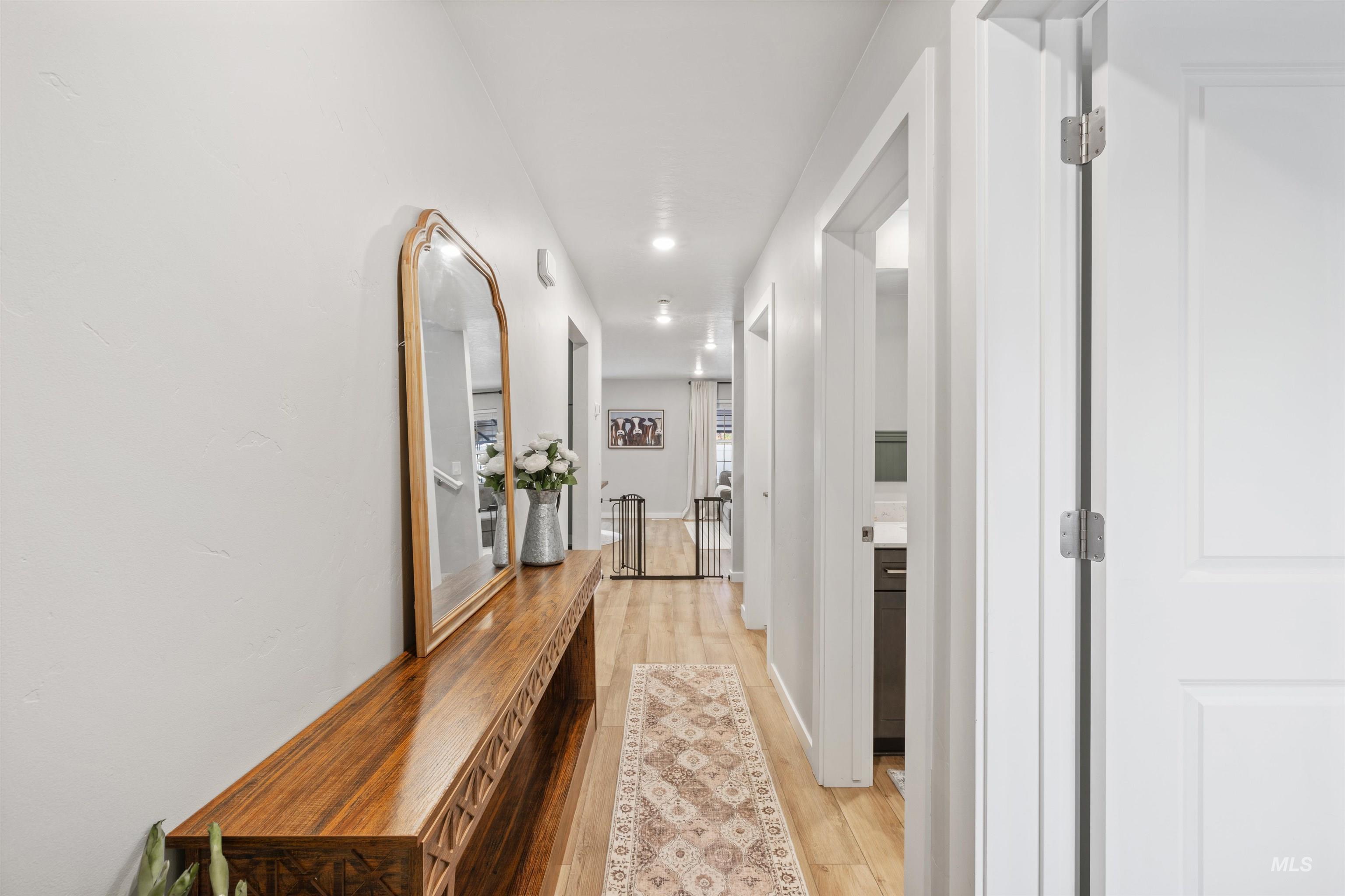Hall with light wood finished floors and recessed lighting