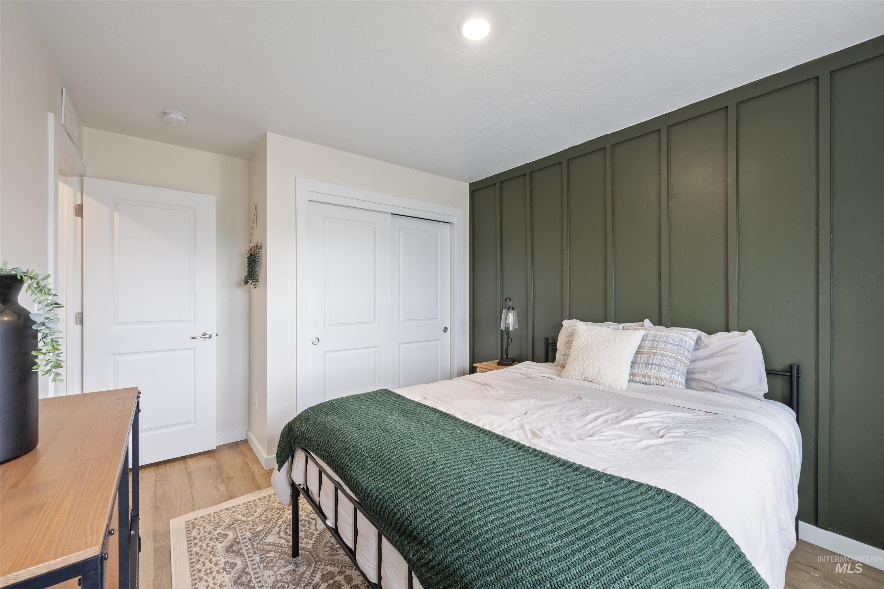 Bedroom featuring a decorative wall, light wood-style flooring, and a closet