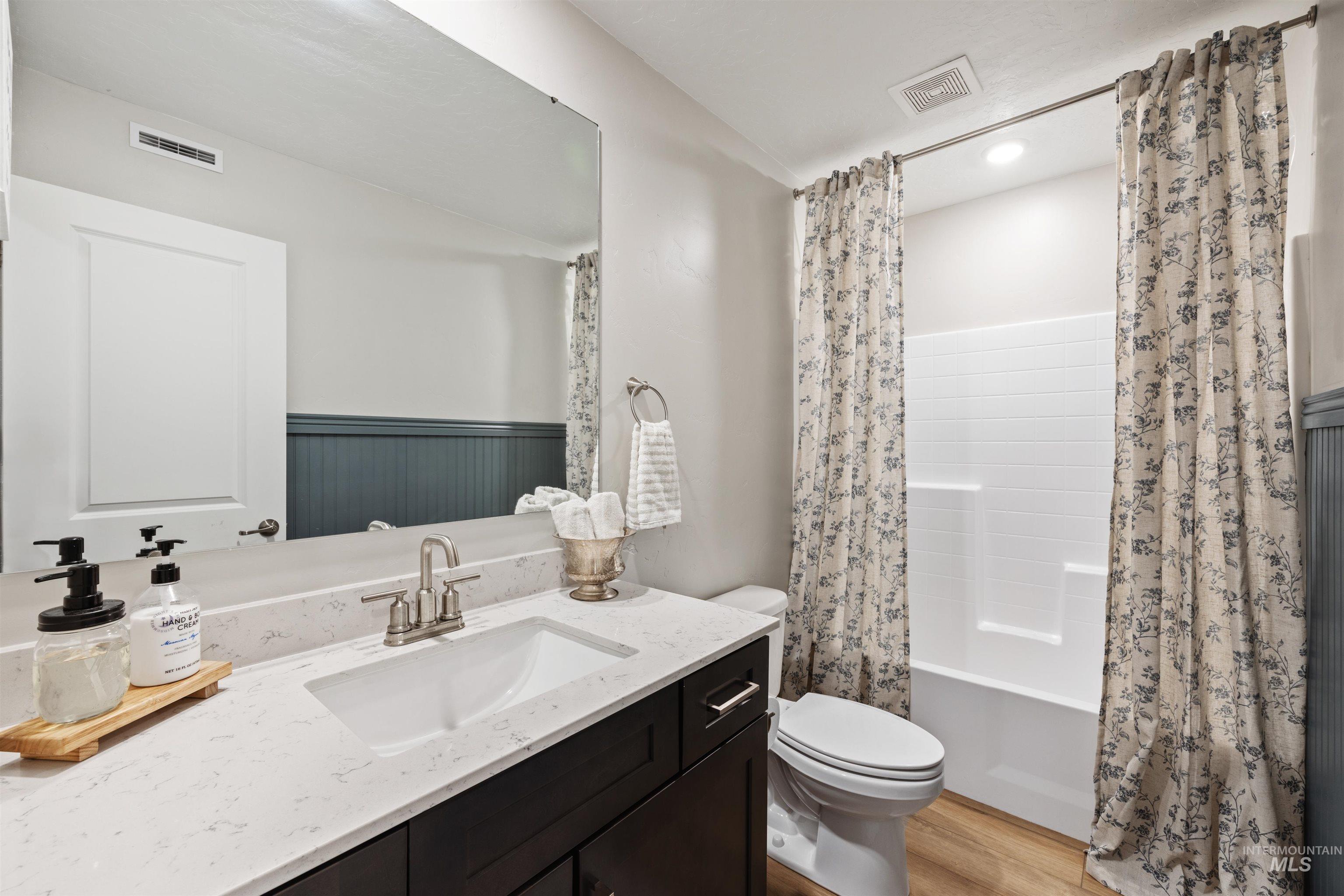 Full bathroom featuring vanity, shower / bath combo with shower curtain, and light wood finished floors
