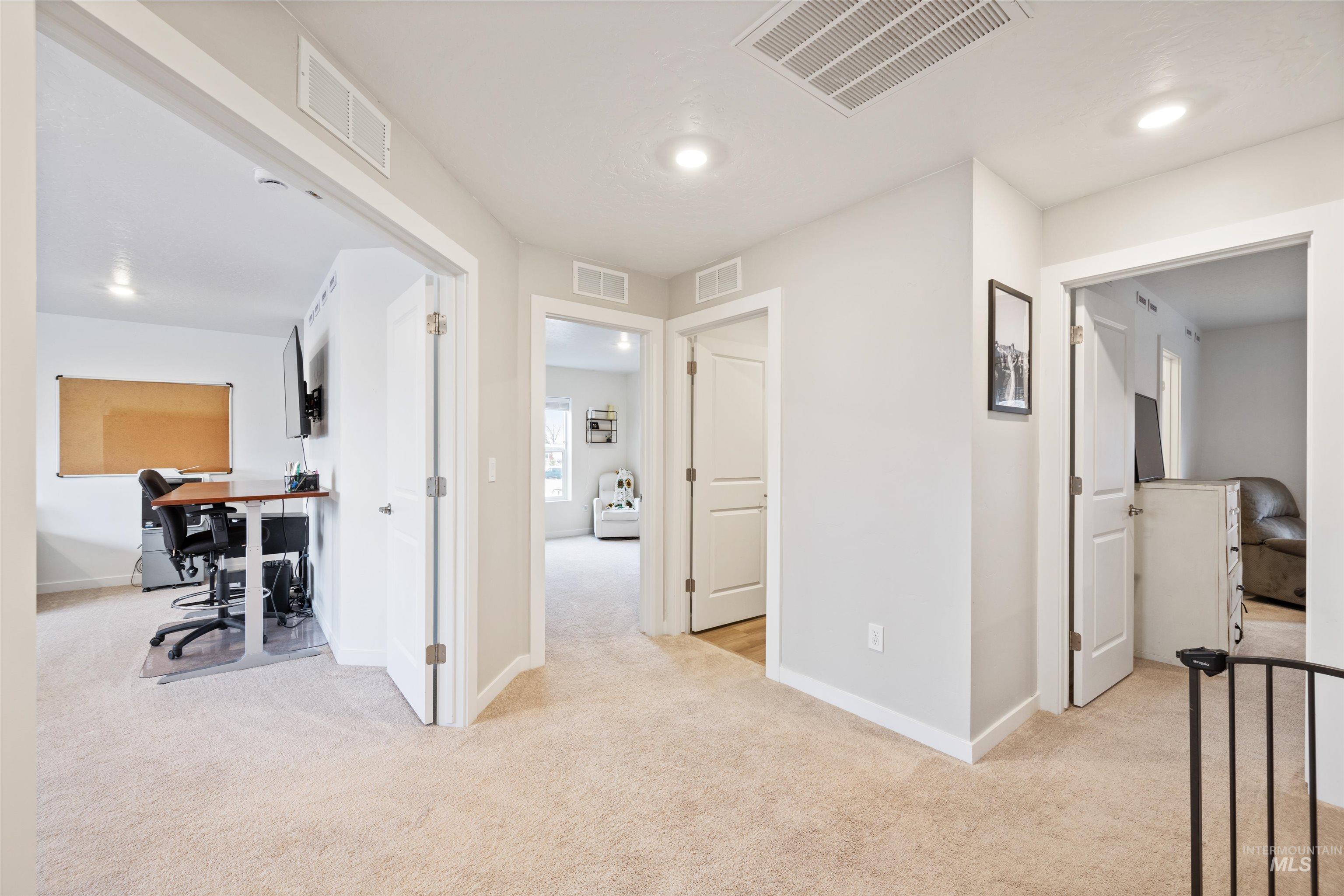Corridor with an office area, light colored carpet, and recessed lighting