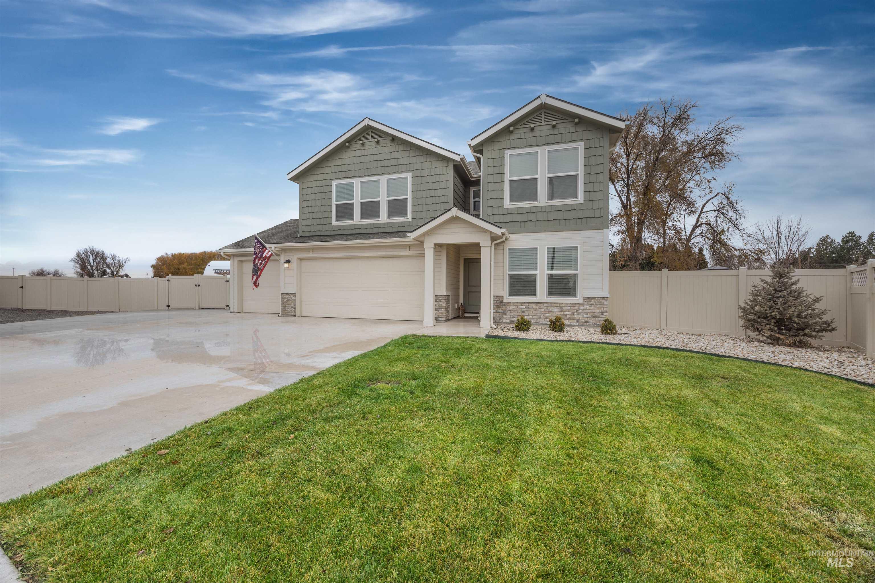 View of front of property featuring stone siding, a gate, concrete driveway, and an attached garage