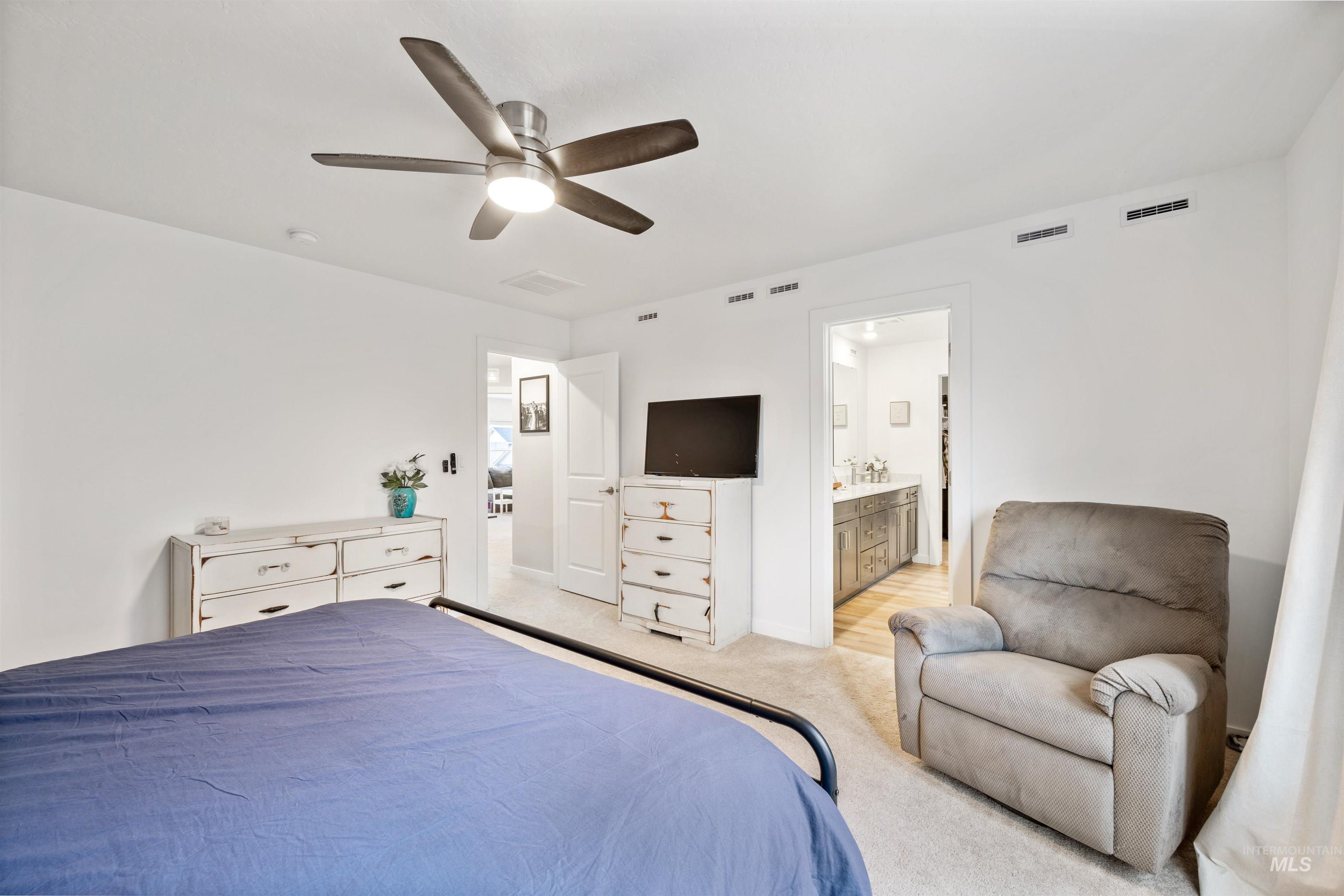 Bedroom with light carpet, ceiling fan, and ensuite bath