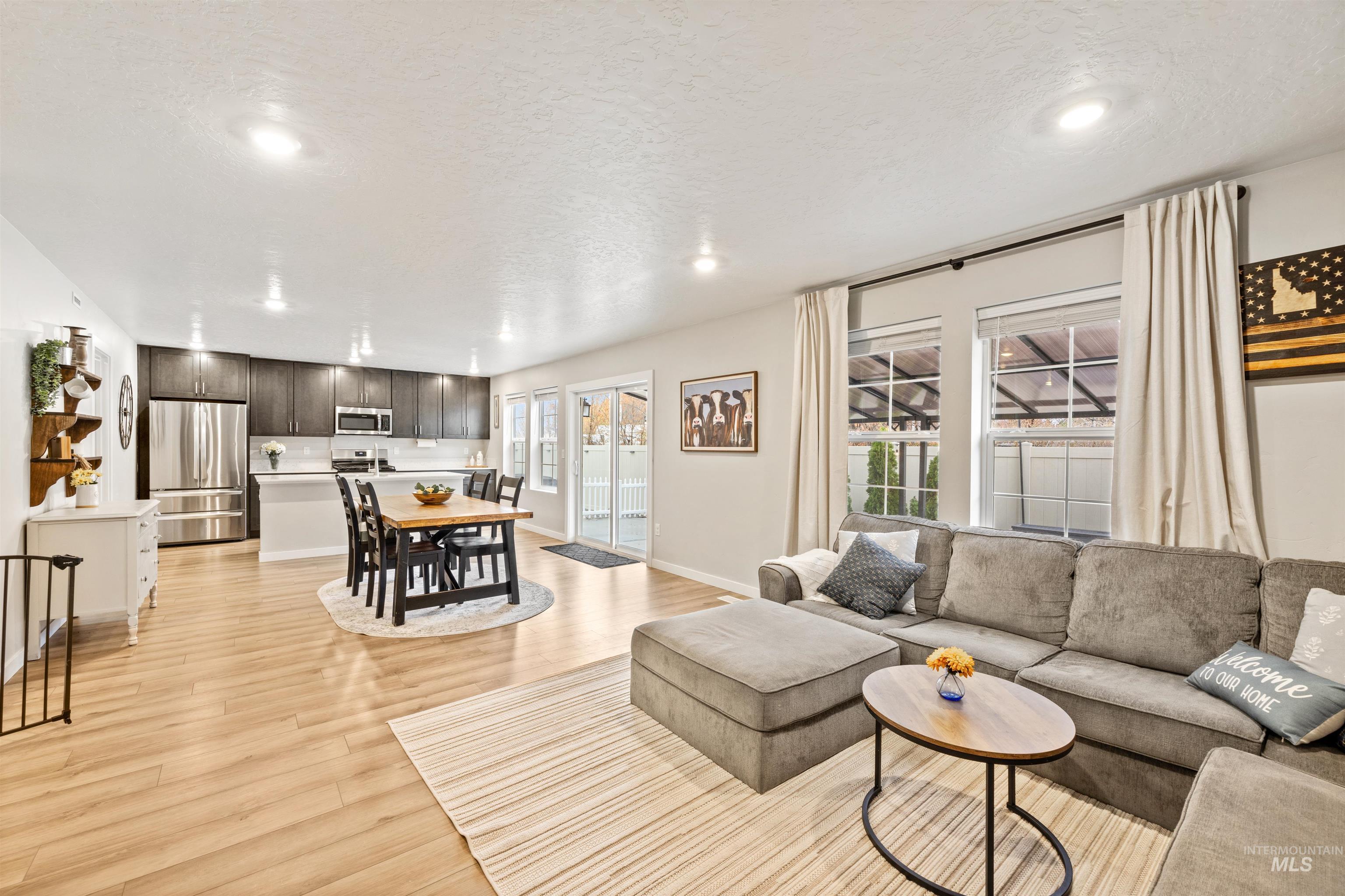 Living area featuring healthy amount of natural light, light wood-style flooring, recessed lighting, and a textured ceiling