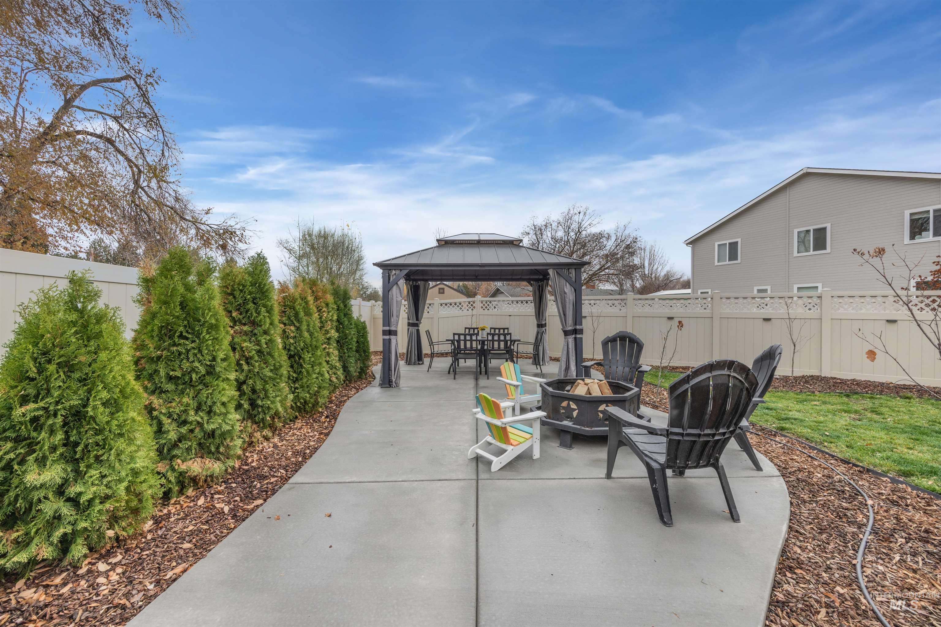 Fenced backyard featuring a patio area, an outdoor fire pit, and a gazebo