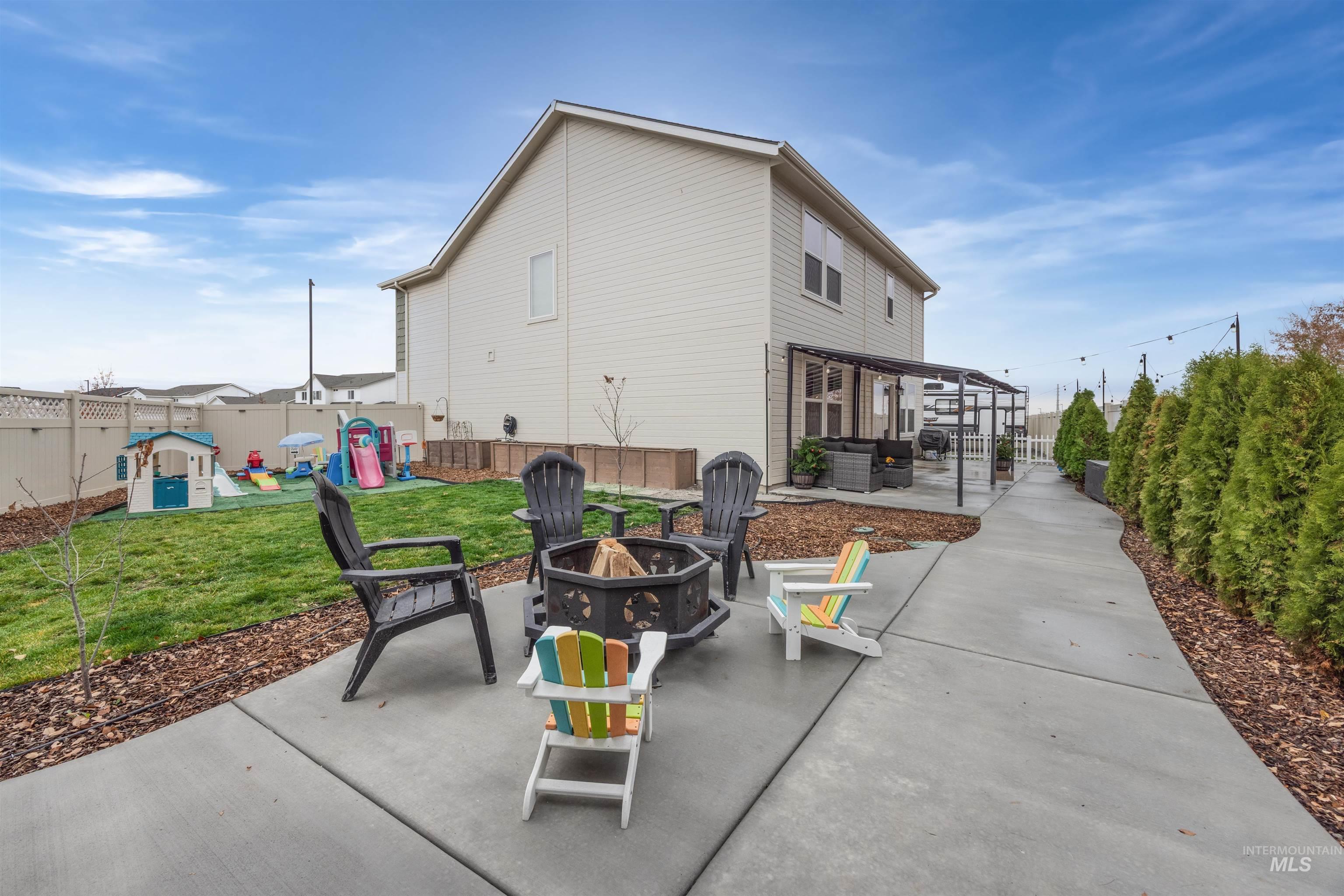 Rear view of property featuring a fire pit, a patio area, a fenced backyard, and a playground