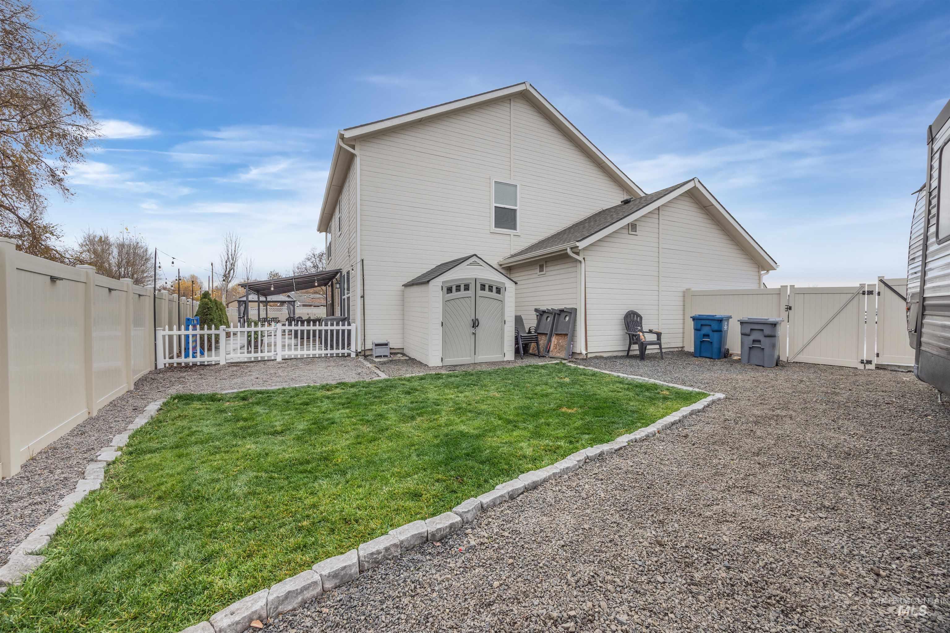 Back of property featuring a gate, a fenced backyard, and a storage unit