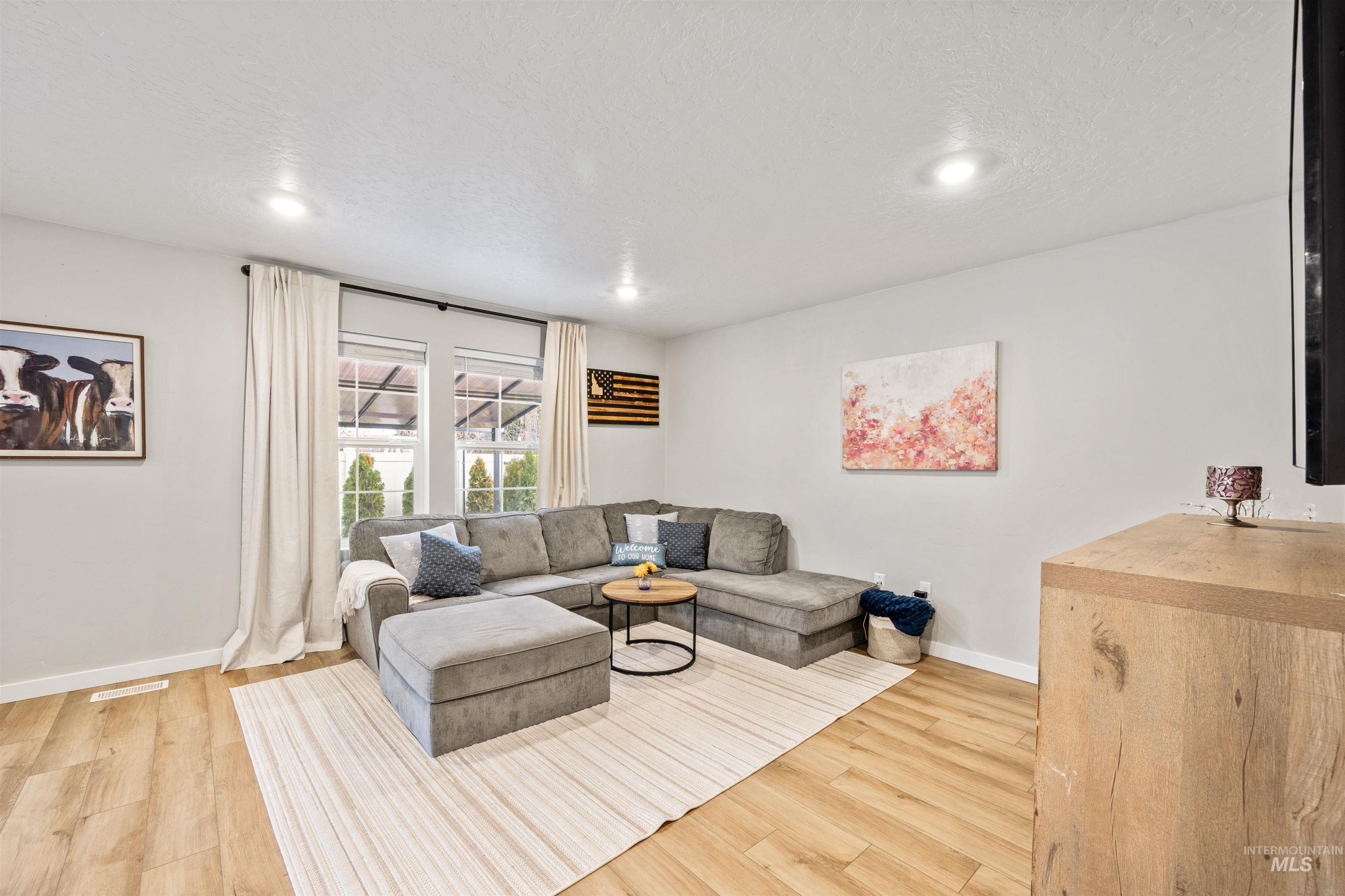 Living room with light wood-style flooring, a textured ceiling, and recessed lighting