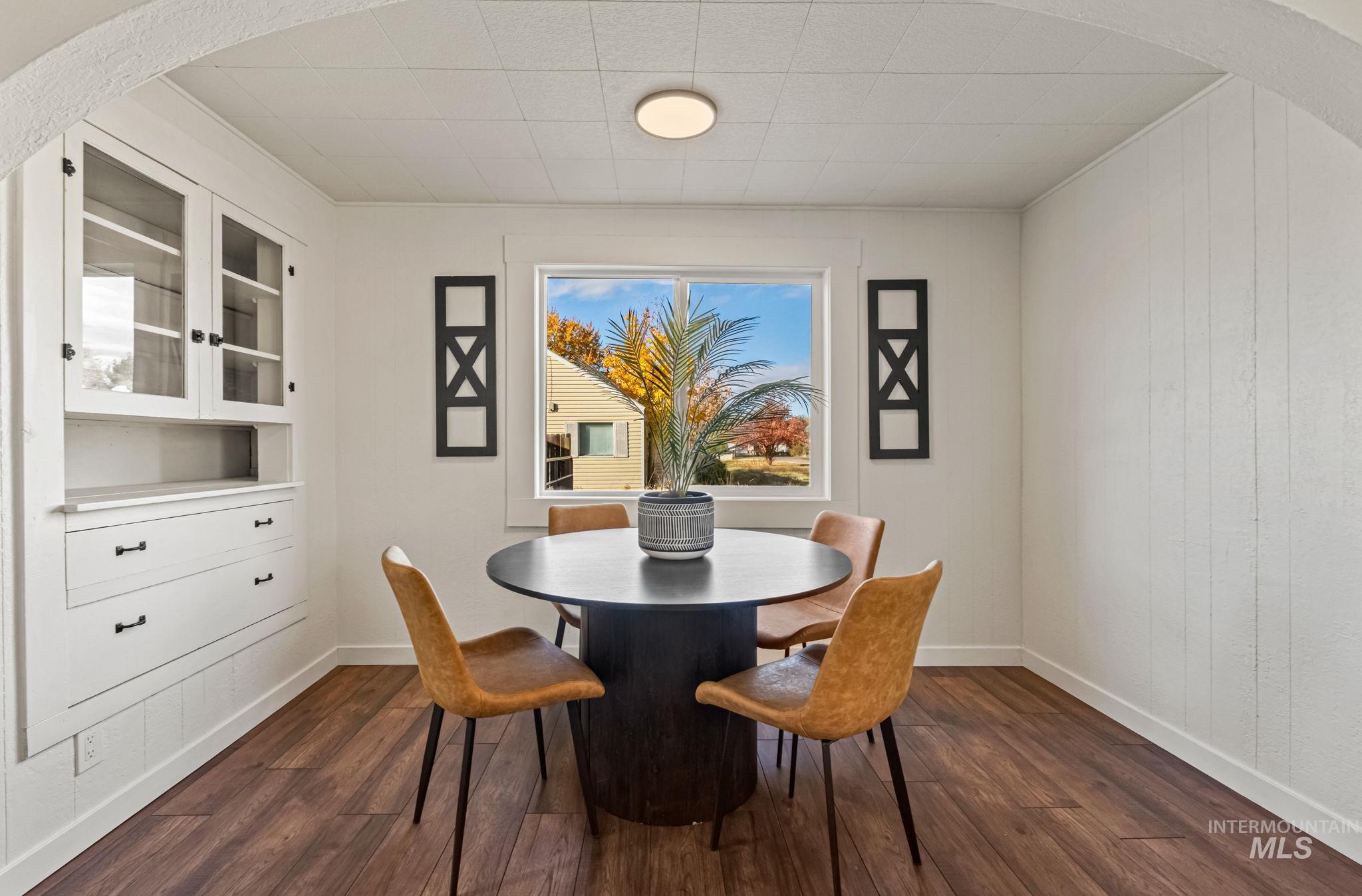 Dining area featuring arched walkways and dark wood finished floors