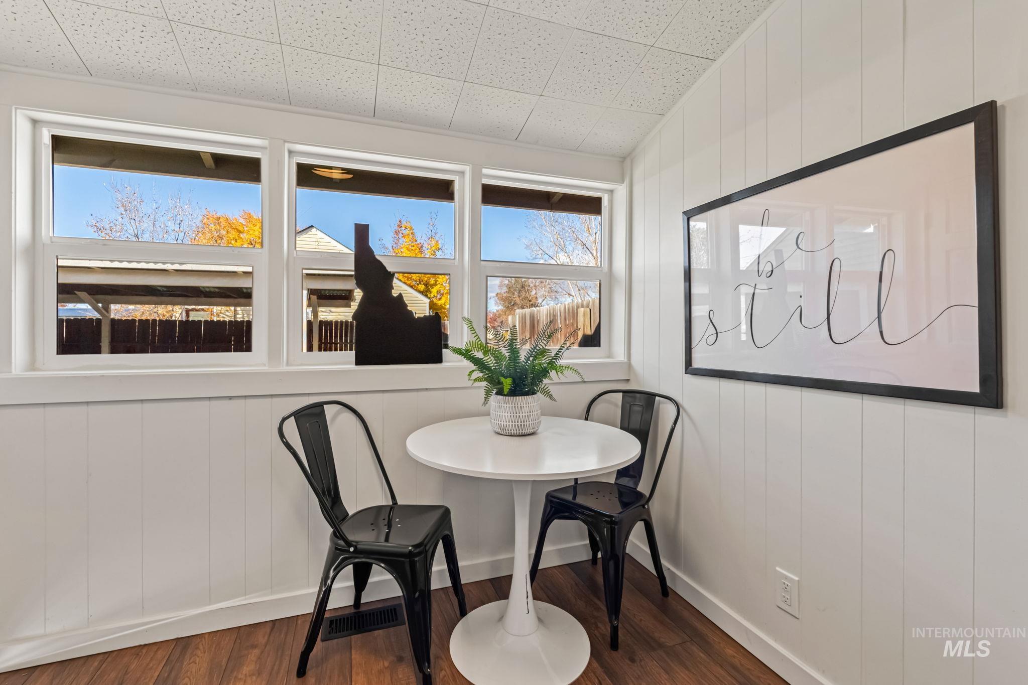 Dining space with dark wood finished floors, wooden walls, and lofted ceiling