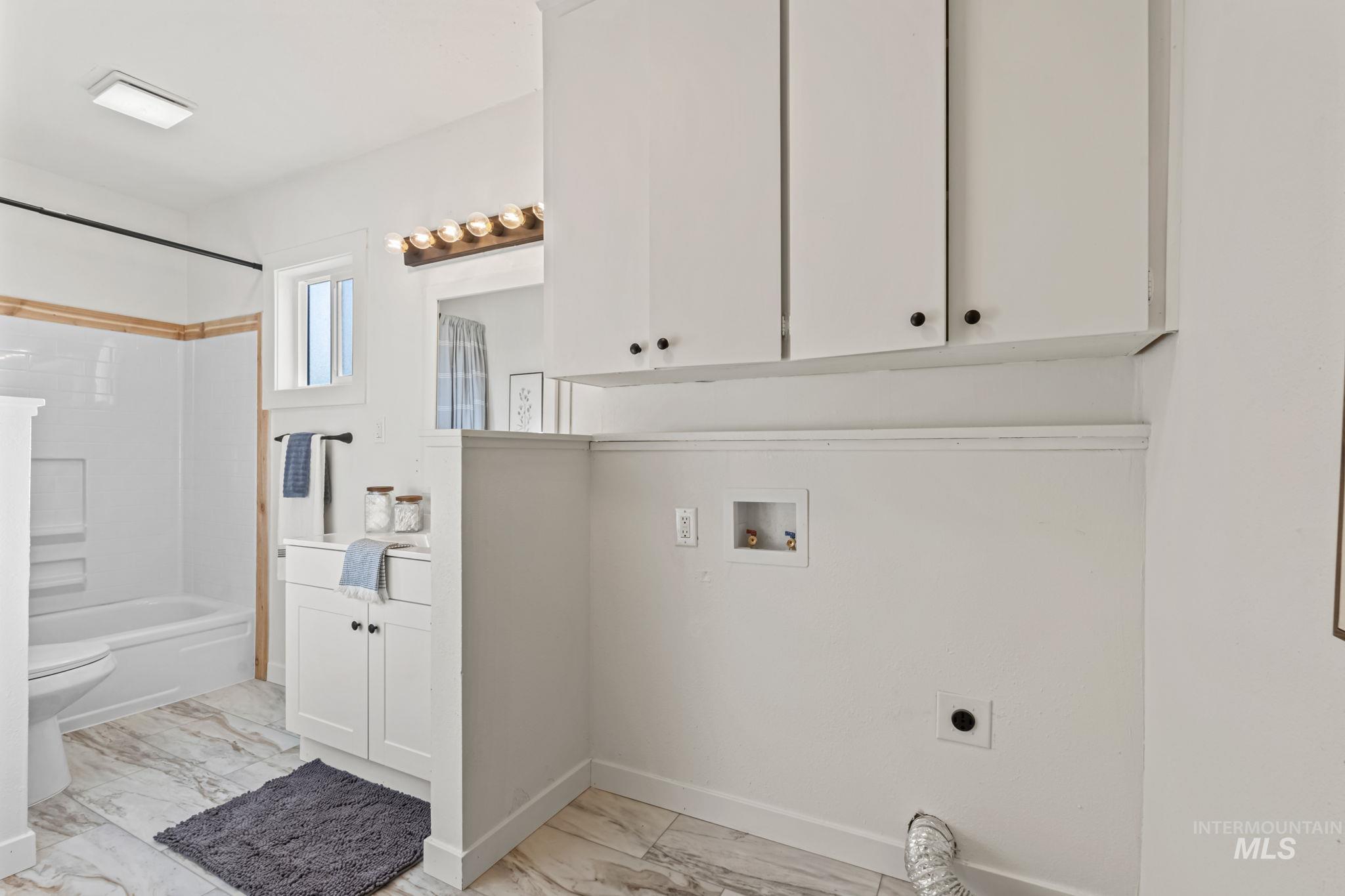 Washroom featuring hookup for a washing machine, hookup for an electric dryer, and light marble finish floors