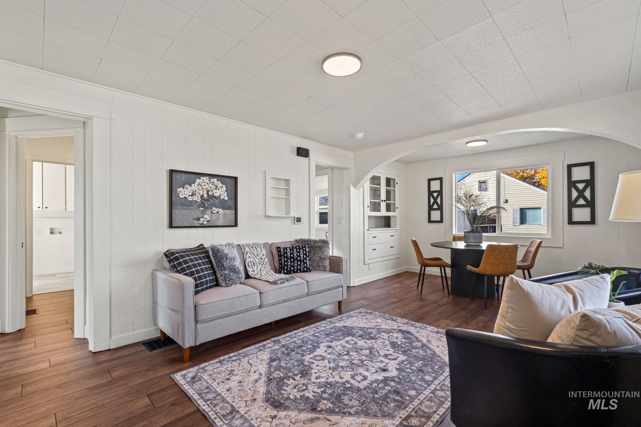 Living room with dark wood-type flooring, wood walls, and arched walkways