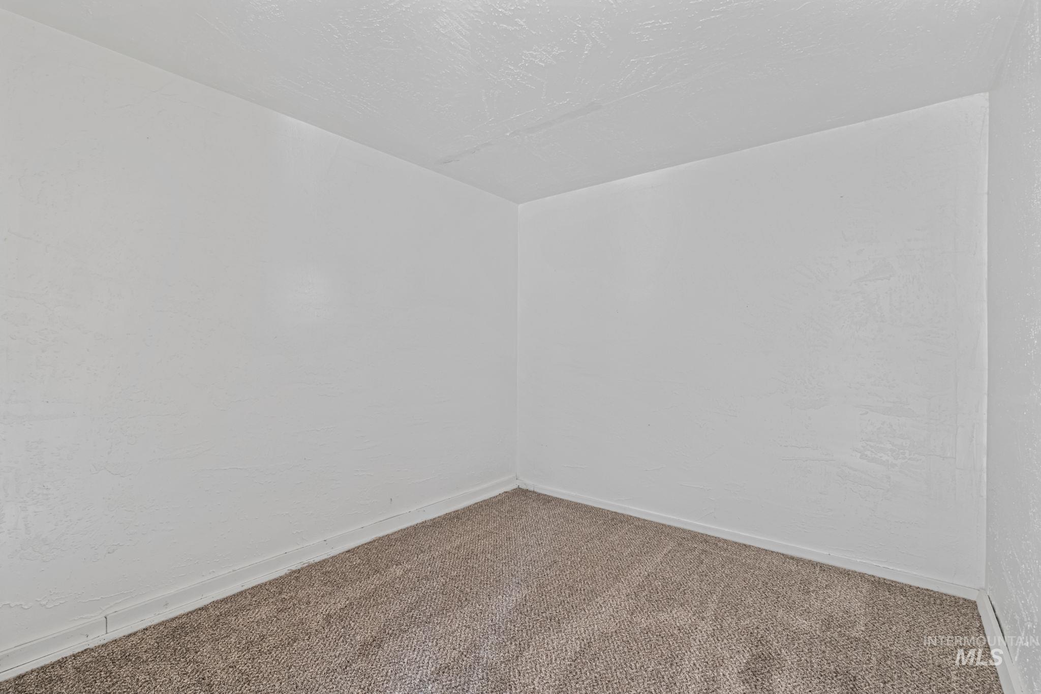 Empty room featuring carpet floors, a textured ceiling, and a textured wall