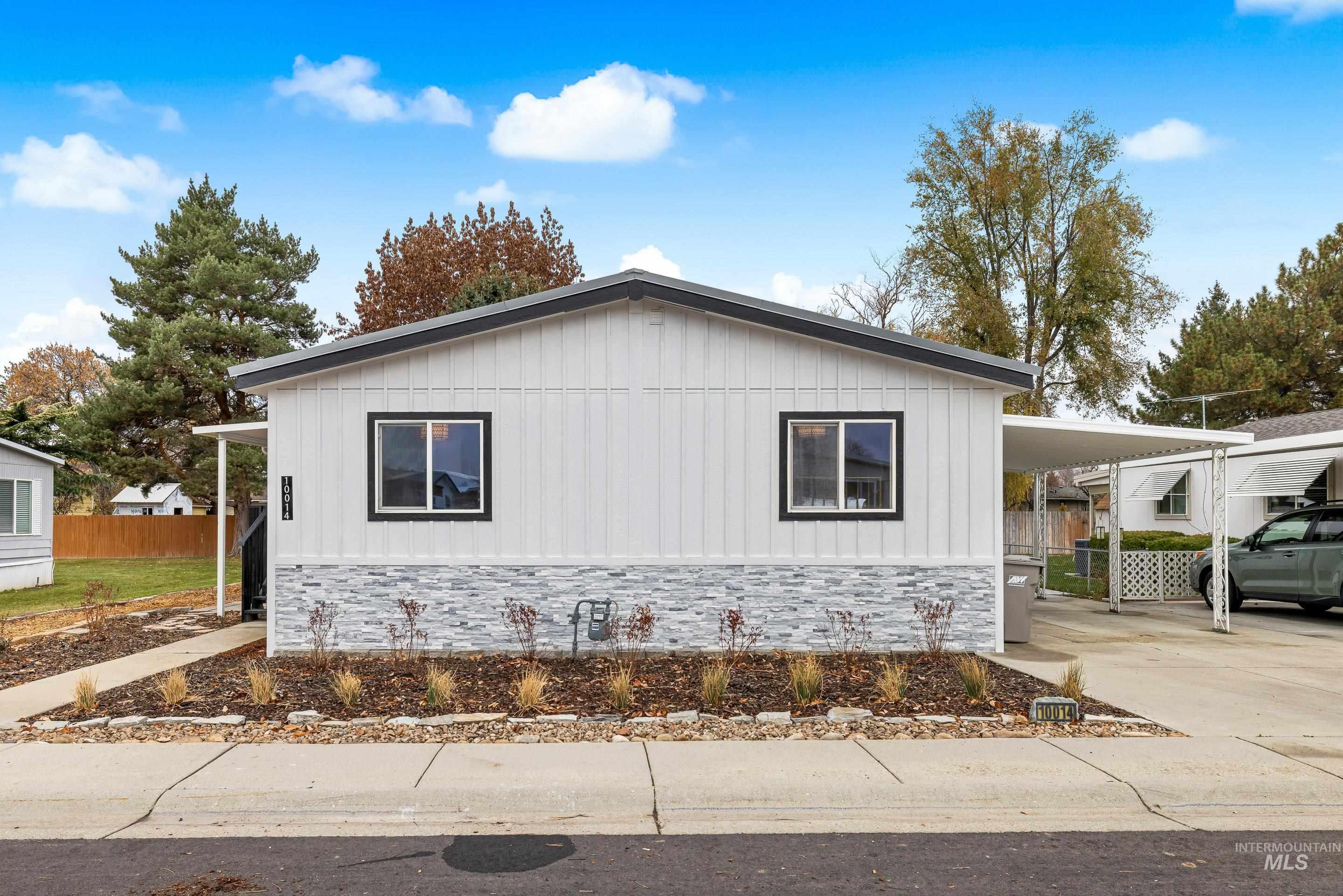 View of home's exterior with stone siding, board and batten siding, concrete driveway, and a carport