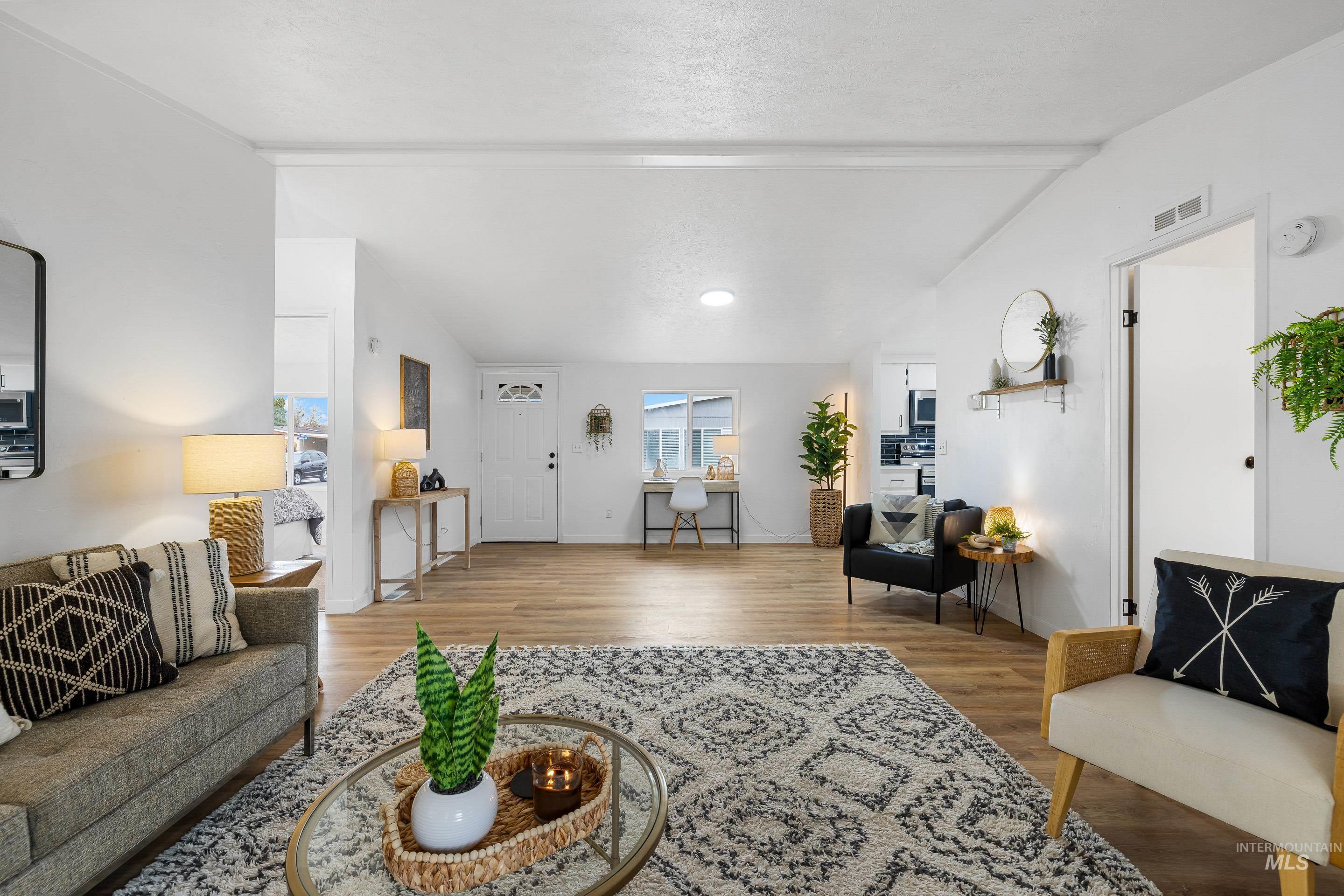 Living area with lofted ceiling, wood finished floors, and a textured ceiling
