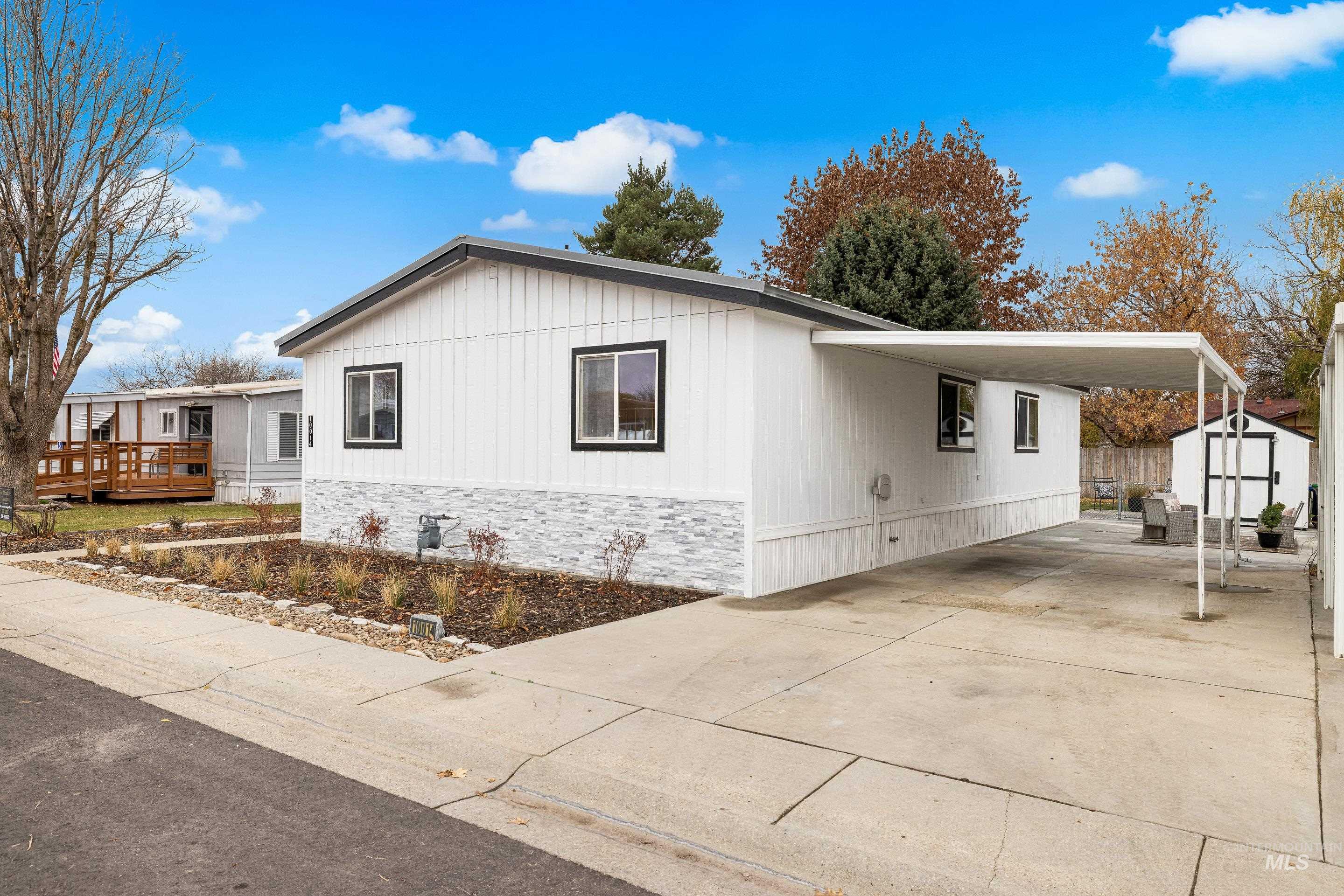 View of side of home with a storage unit, driveway, an attached carport, and a deck