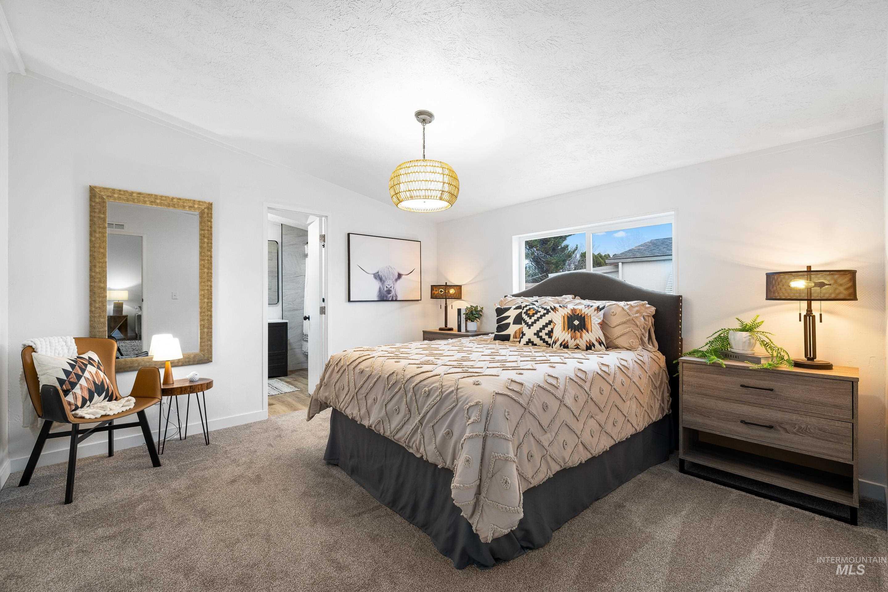 Bedroom with a textured ceiling, connected bathroom, and carpet